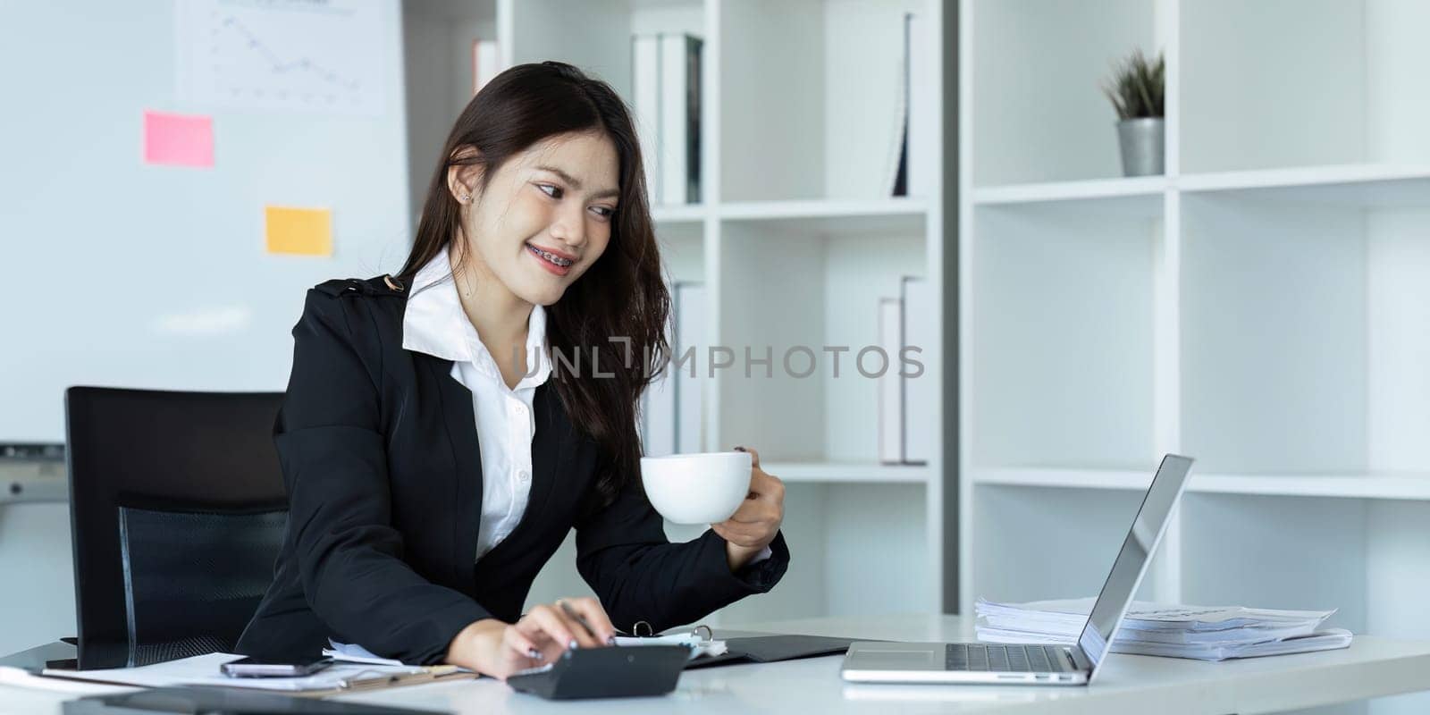 businesswoman working with documents and laptop, worker paperwork calculates financial indicators smiling.