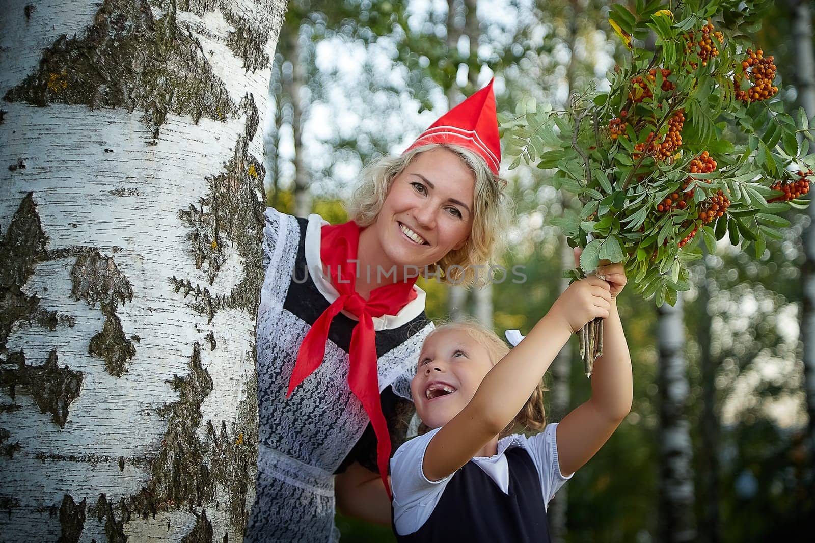 Young and adult schoolgirl on September 1, mother and daughter having fun and joy. Generations of schoolchildren of USSR and Russia. Female pioneer in red tie and October girl in modern uniform