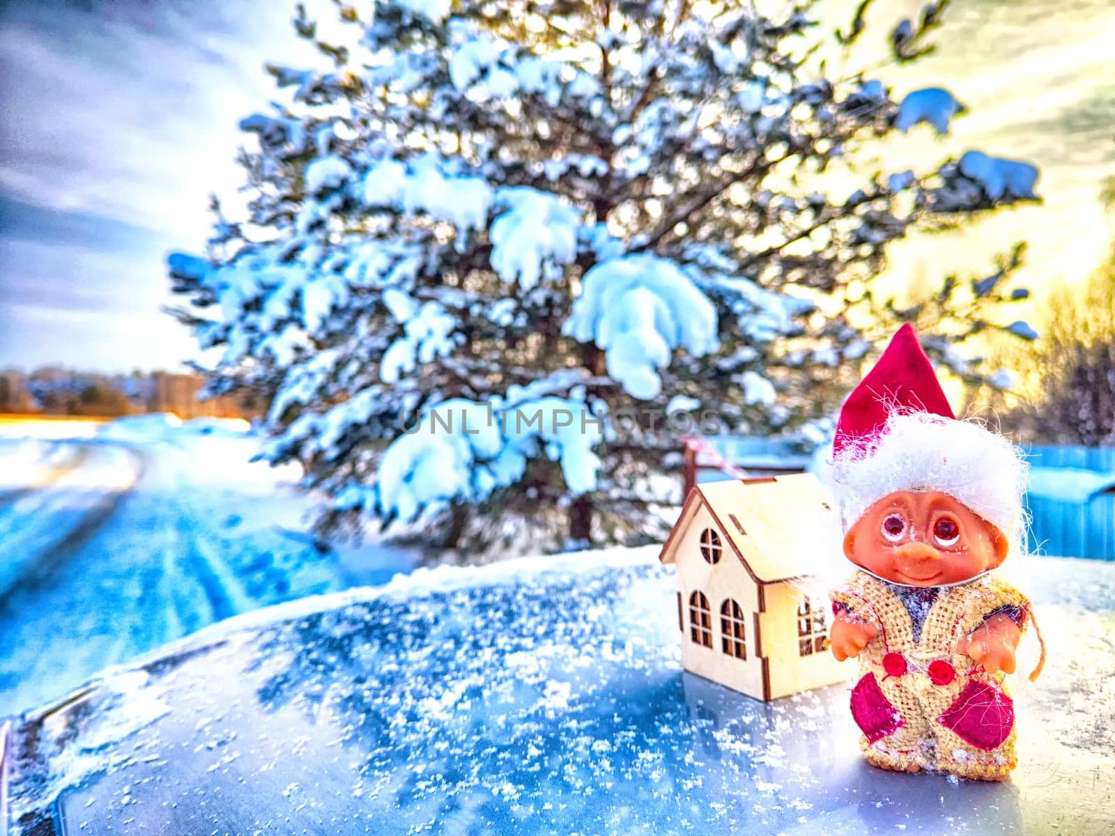 Cute little funny dwarf and small wooden house in snow in winter landscape. Wizard on snowy background. Christmas and New Year