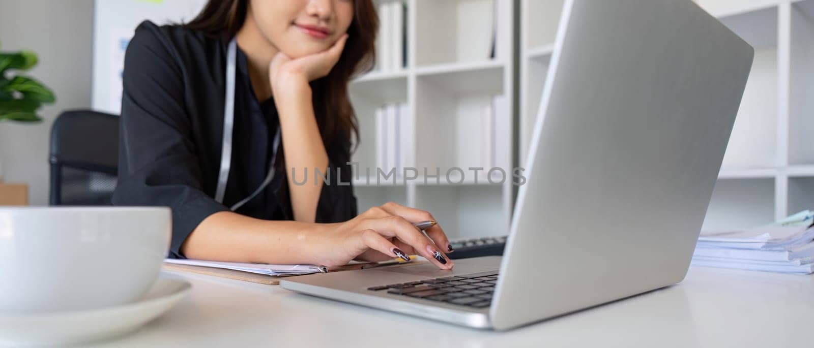 Businesswoman working using laptop computer to record and print information for a marketing plan analyze the balance sheet report financial statement.