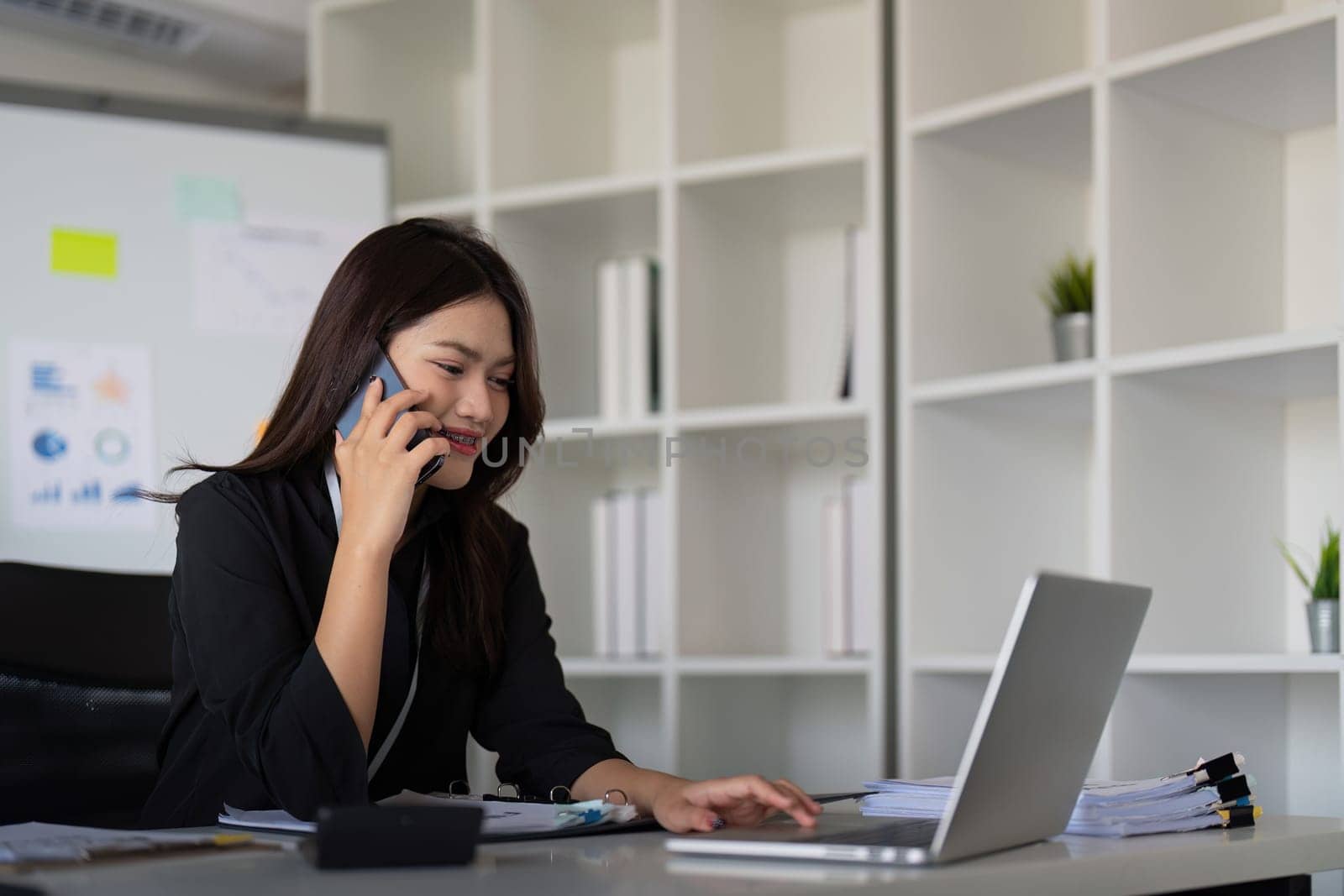 Happy confident businesswoman talking on the phone. Smiling female business person talking work using talking on the phone at office sitting at desk by nateemee