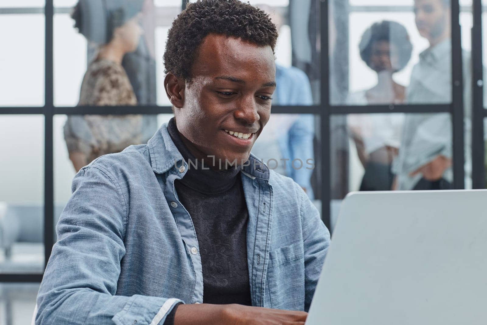 smiling leader business man with executives working on laptop in background.