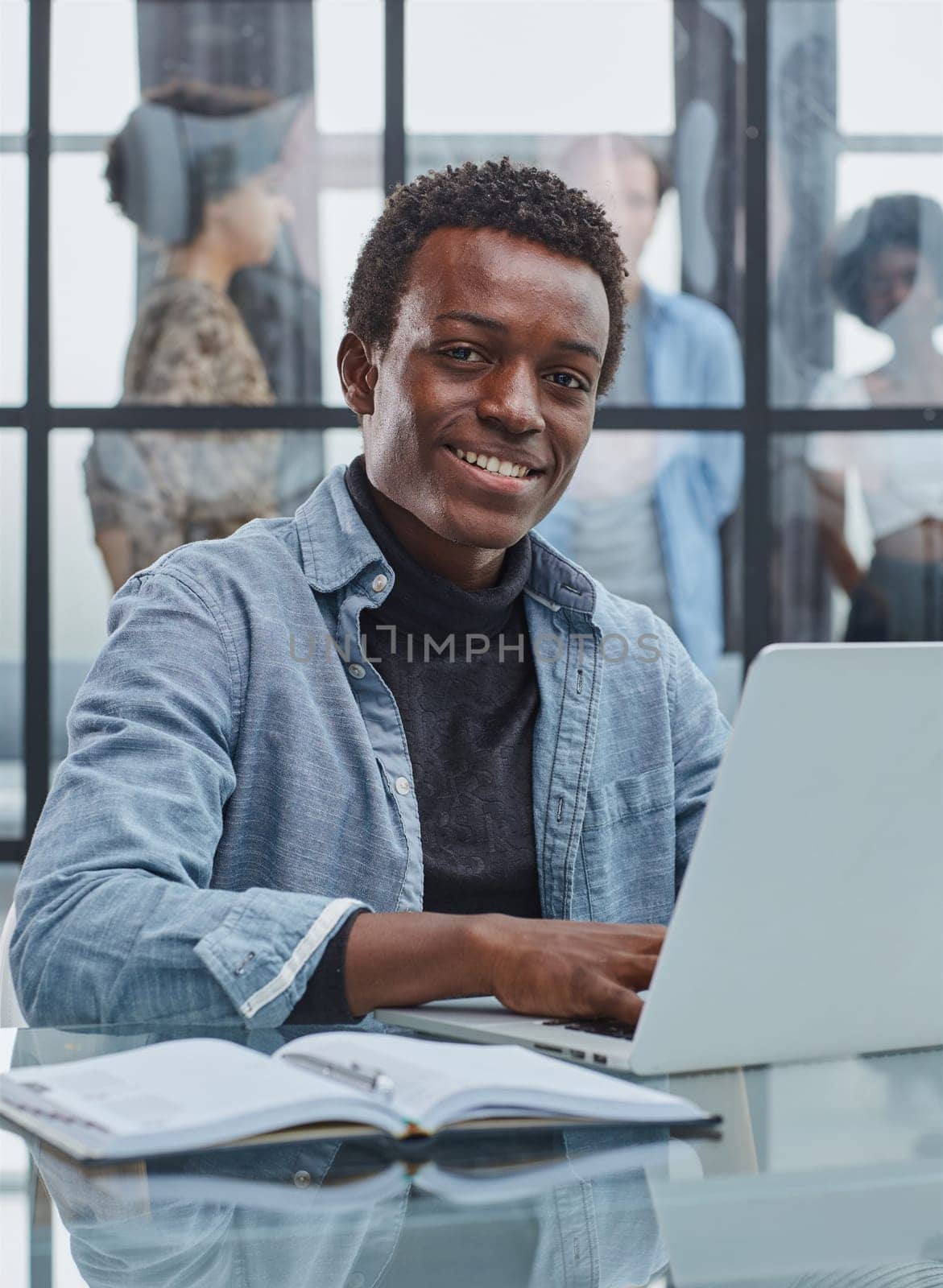 smiling leader business man with executives working on laptop in background.