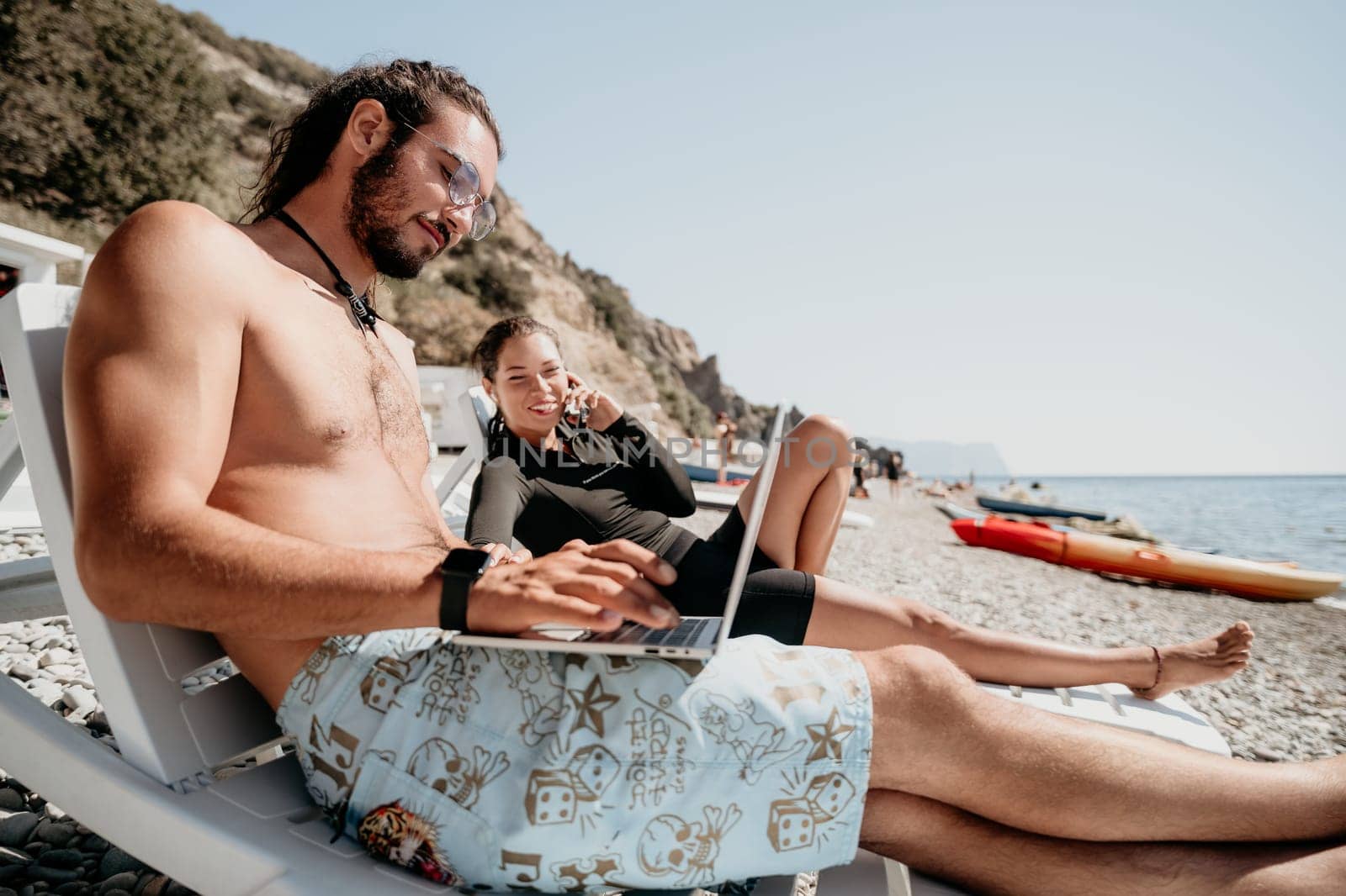 Digital nomad, Business man working on laptop by the sea. Man typing on computer by the sea at sunset, makes a business transaction online from a distance. Freelance, remote work on vacation