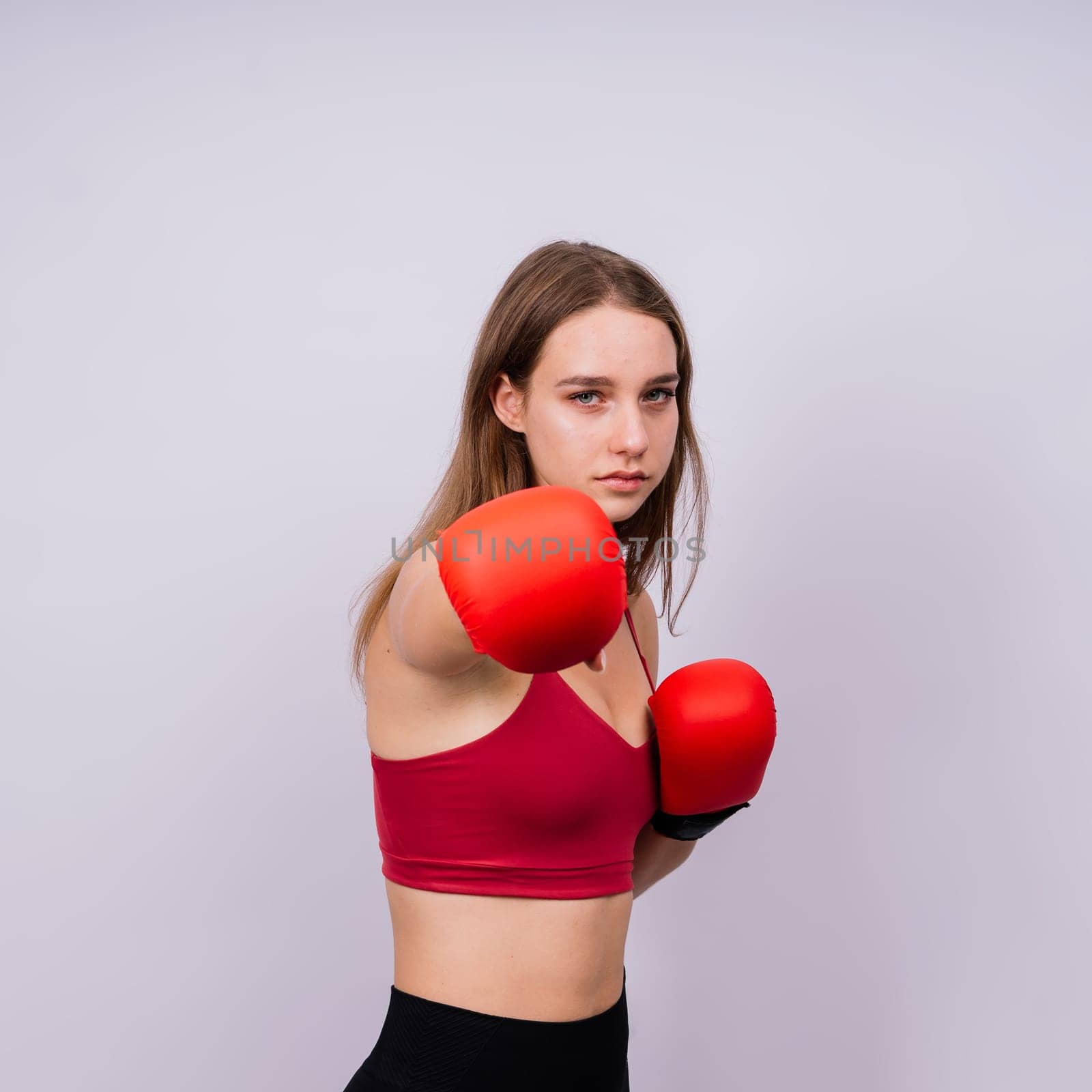 Woman boxer in gloves training on grey and yellow background studio by Zelenin