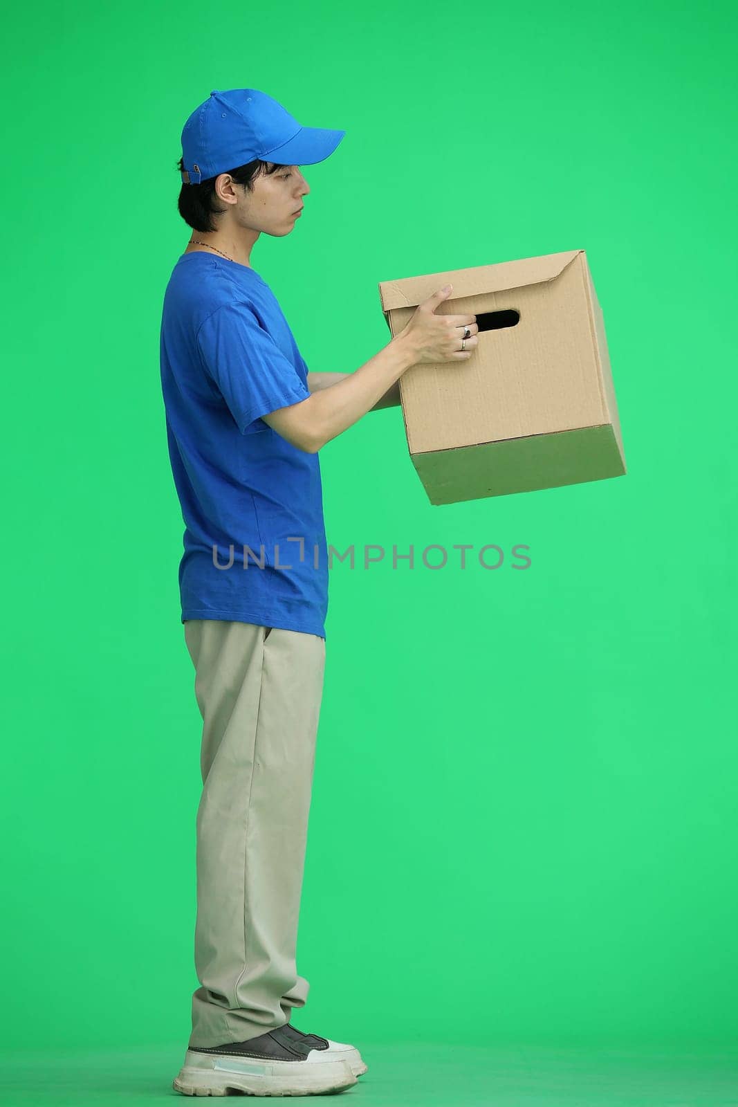 The delivery guy, on a green background, full-length, with a box.