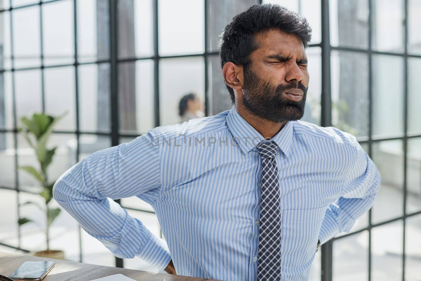 Guy Having Backache Massaging Aching Lower Back Suffering From Pain Sitting At Workplace In Modern Office