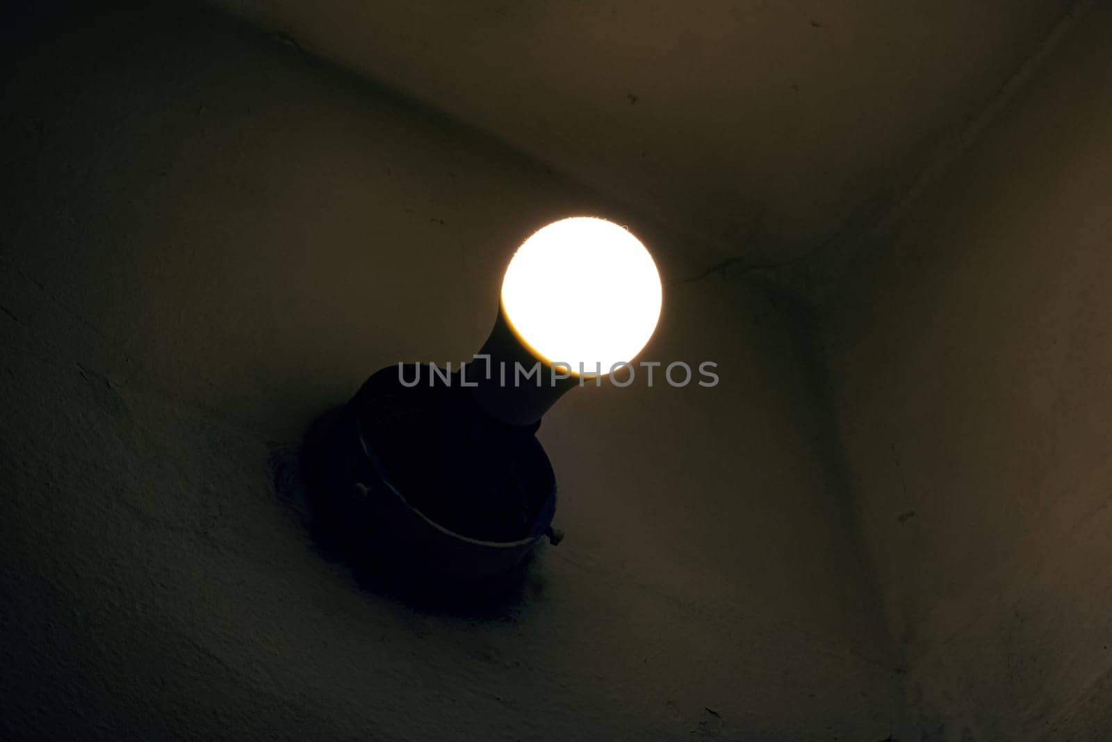 Light of an old light bulb on a wall in the dark close up