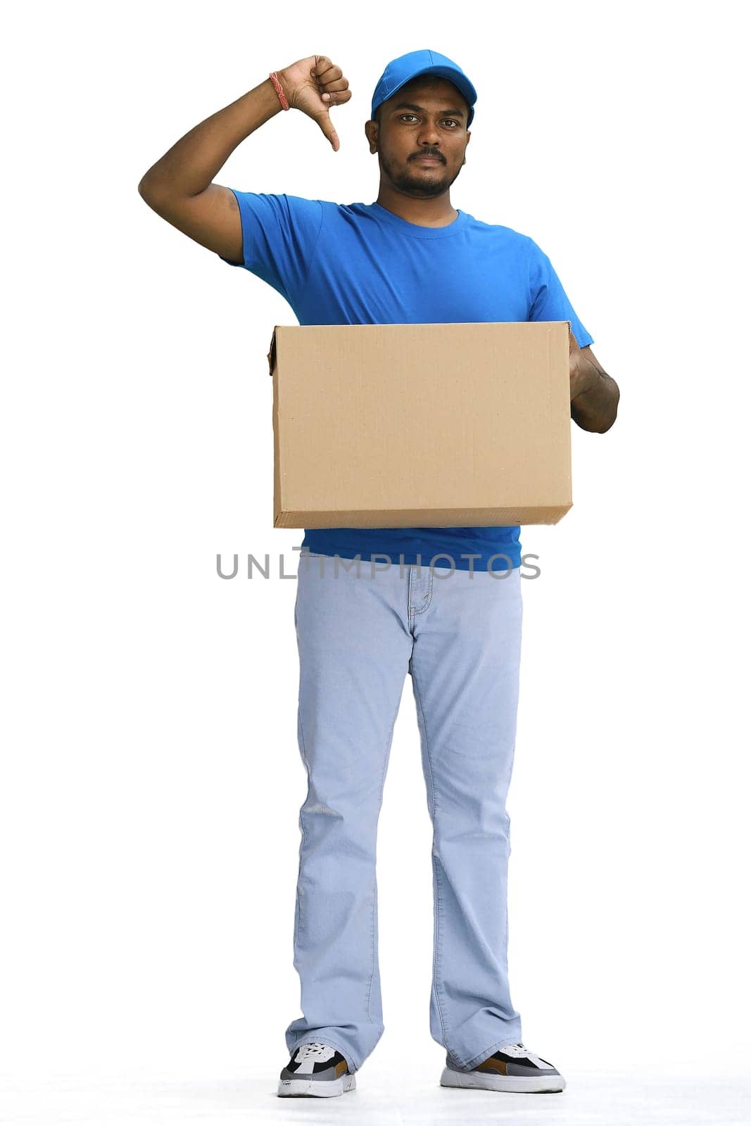 A male deliveryman with a box, on a white background, in full height, points at himself.