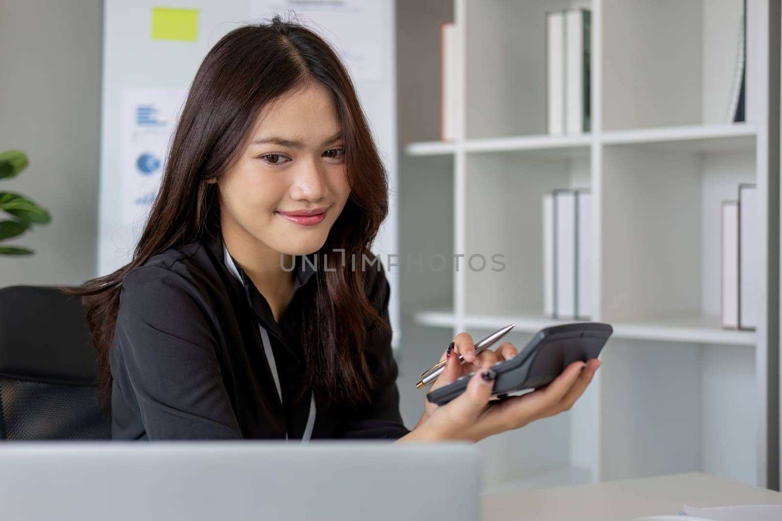 Business woman using calculator and laptop for do math finance on wooden desk in office and business working background, tax, accounting, statistics and analytic research concept by wichayada