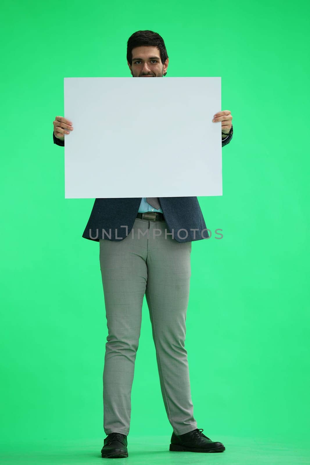 A man in an office suit holds a white sheet in front of him.