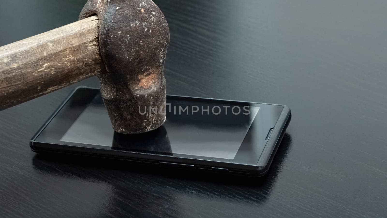 Phone under hammer close up on wooden table