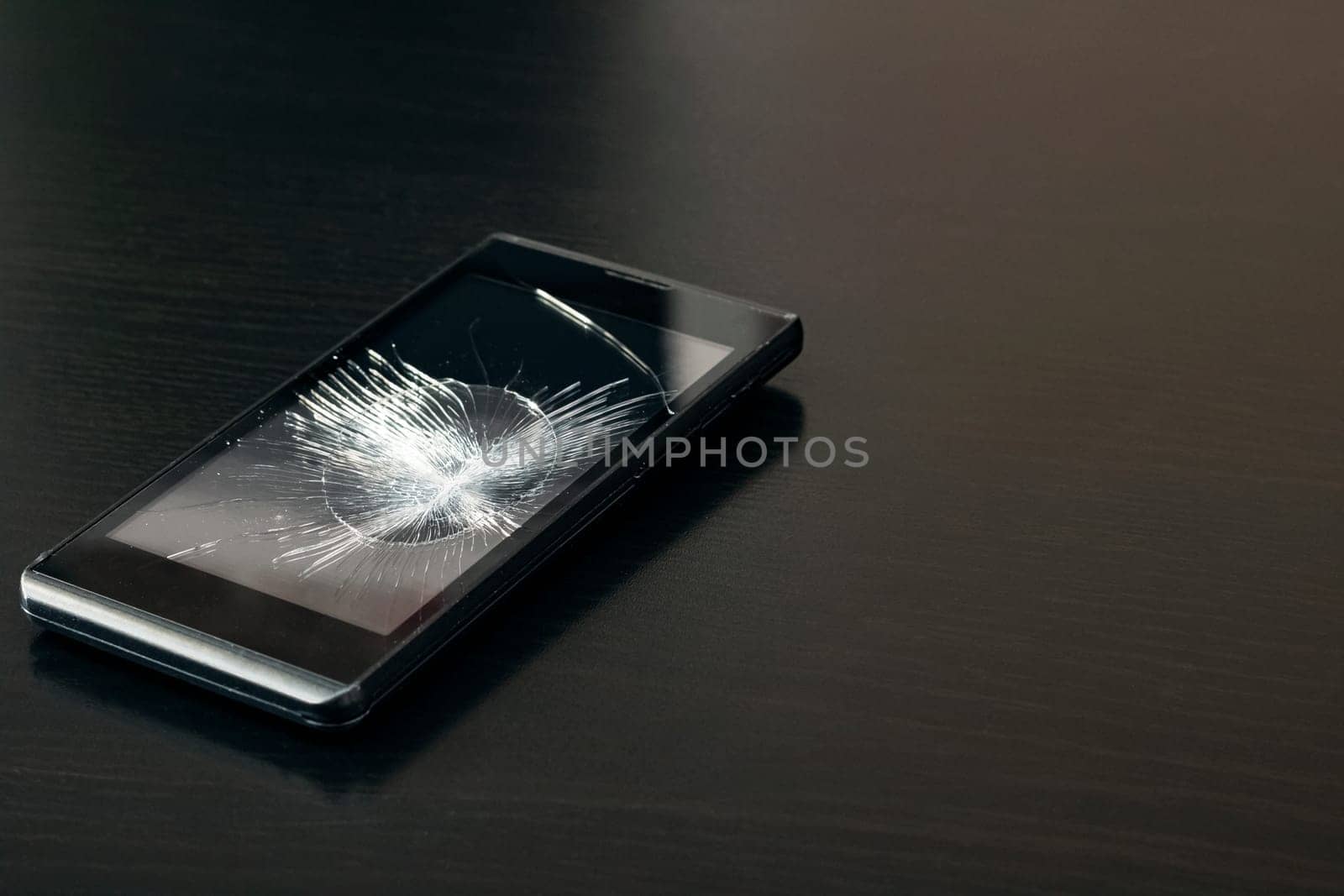 Broken display phone on a black wooden table