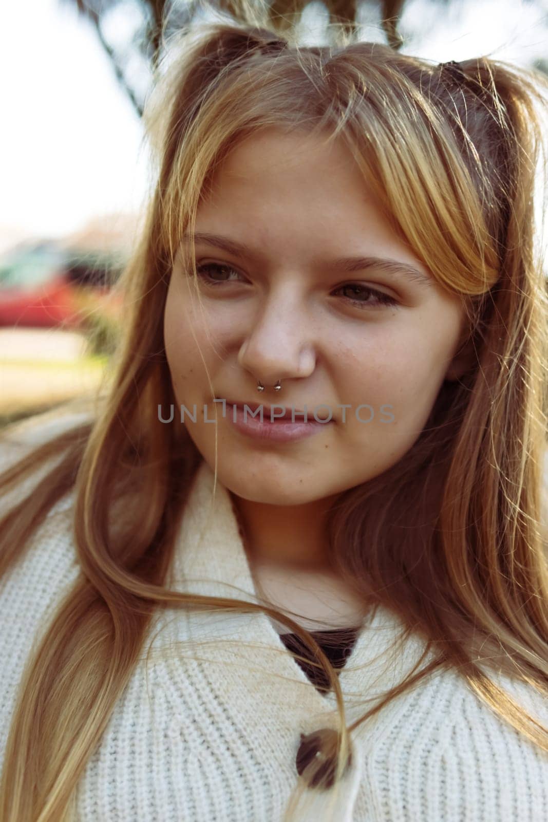 vertical photo Young woman with a nose piercing against a blurred street background, close-up by PopOff