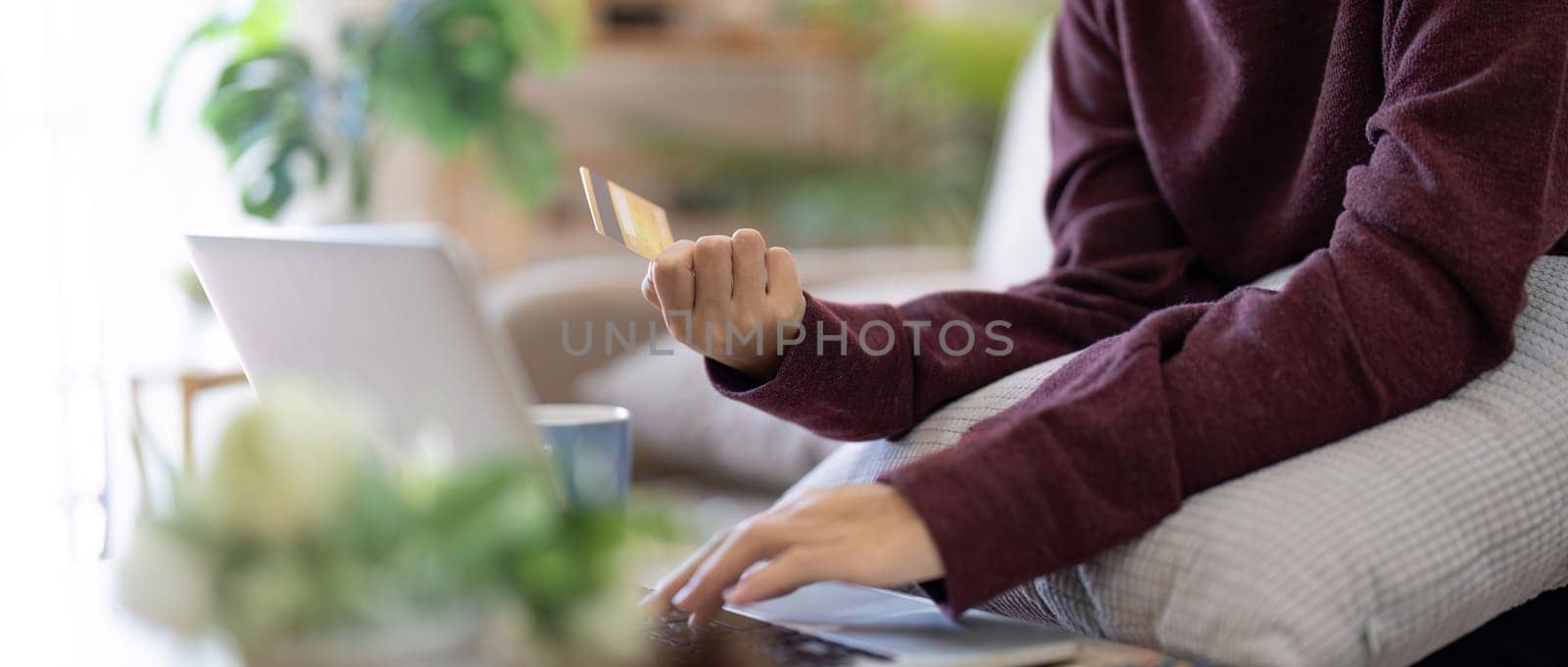 Woman is doing online purchase. Girl is doing shopping using laptop computer and credit card for payment at home.