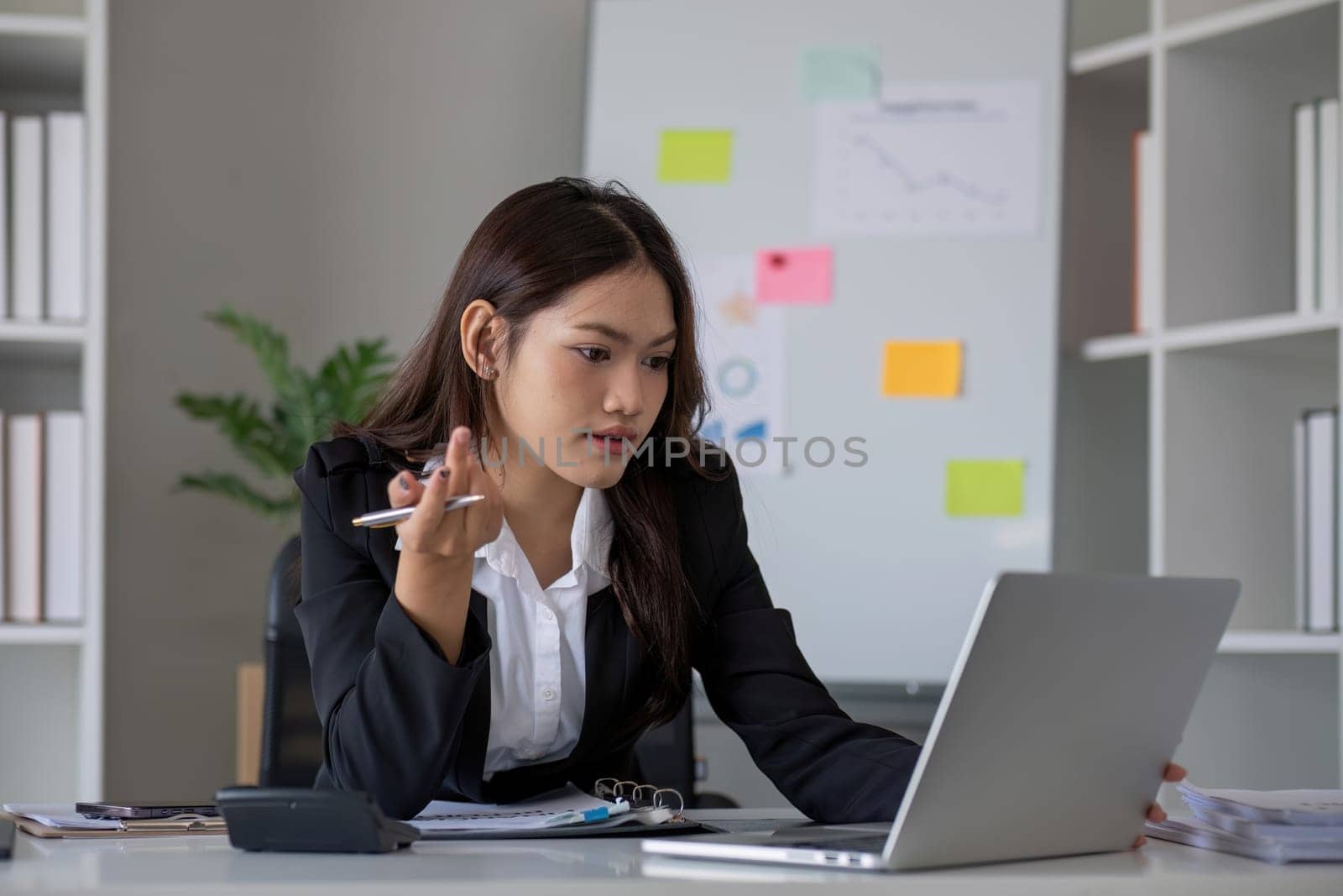 Portrait of young Asian woman working on laptop in modern office Perform accounting analysis, report investment data. Financial concepts and tax system.