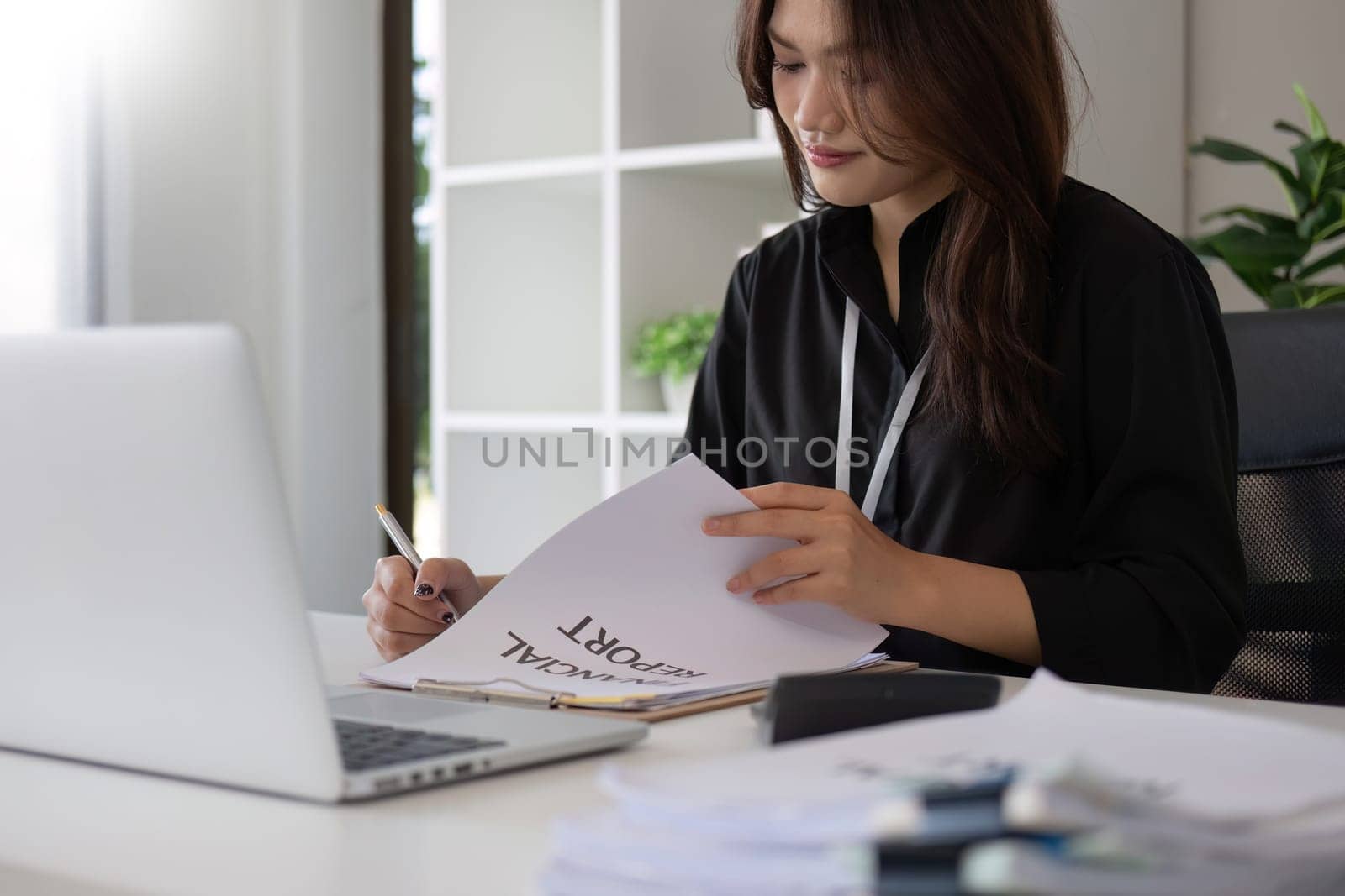 Portrait of young Asian woman working on laptop in modern office Perform accounting analysis, report investment data. Financial concepts and tax system.