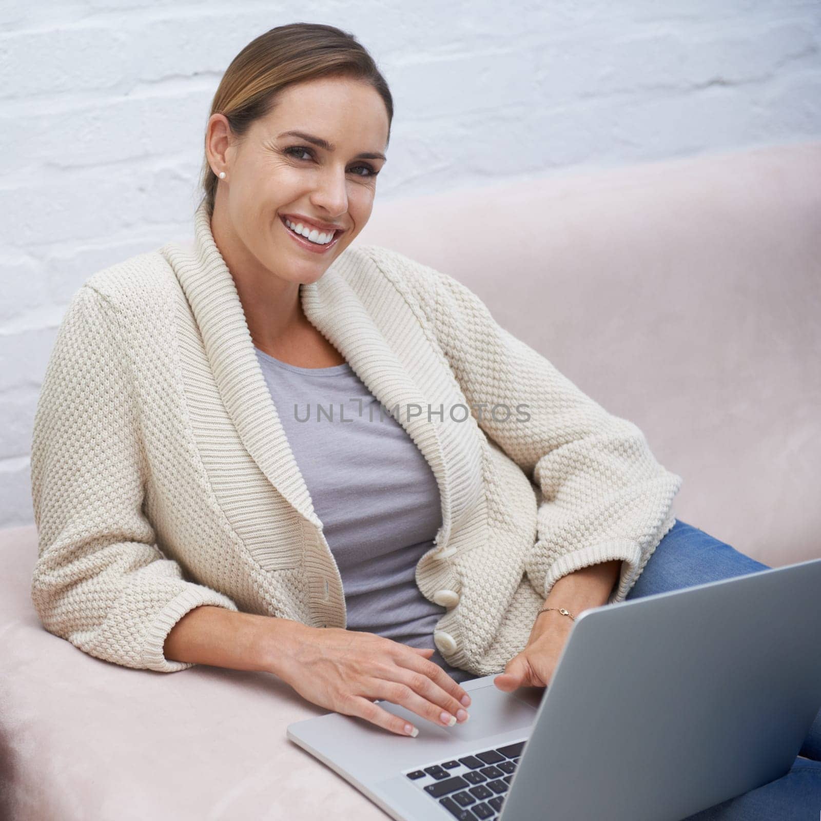 Woman, laptop and happy on sofa with portrait for relax, communication or typing in living room of home. Person, technology and smile for networking, streaming or research on internet or web on couch by YuriArcurs