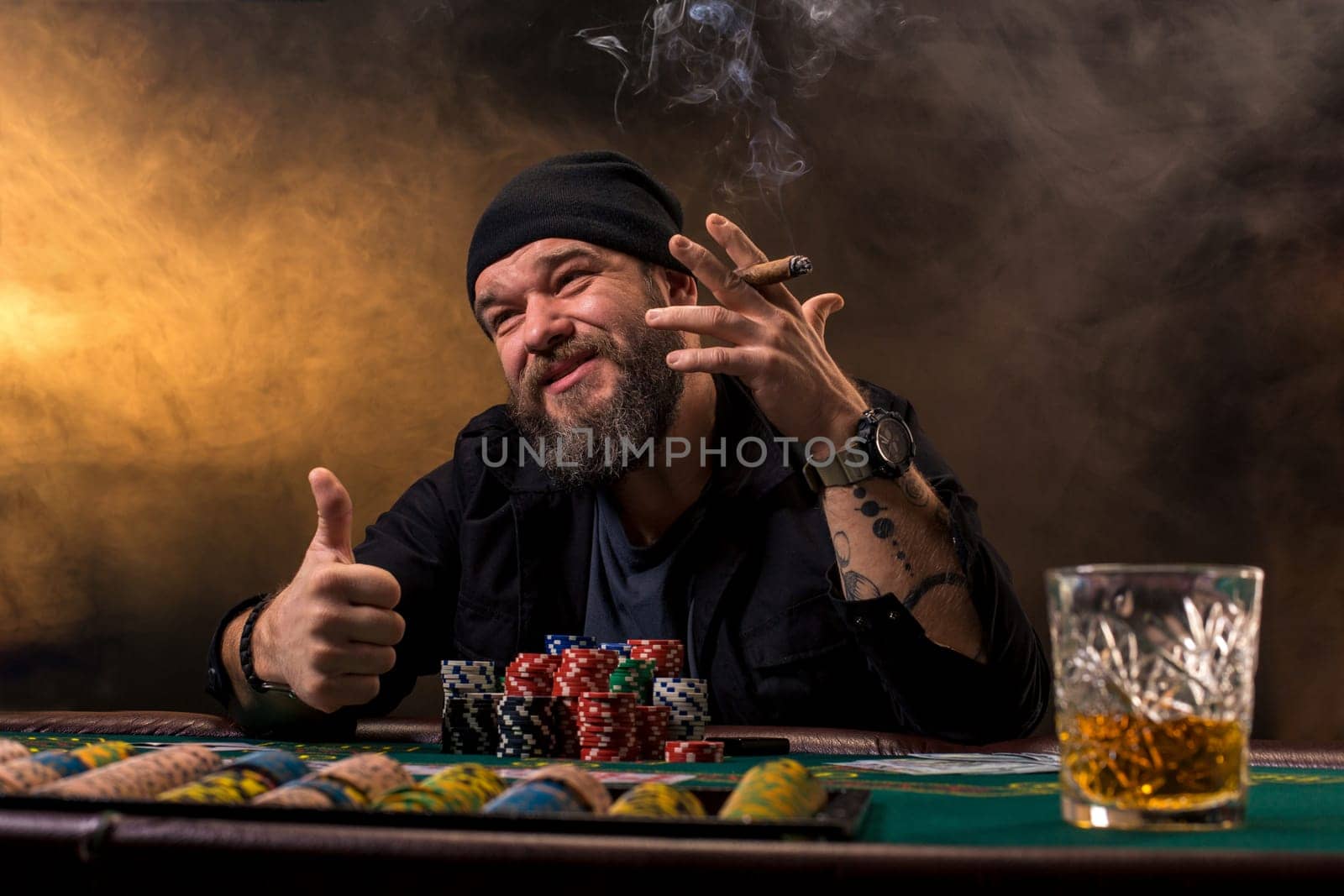 Bearded man drinking whisky while playing poker by nazarovsergey