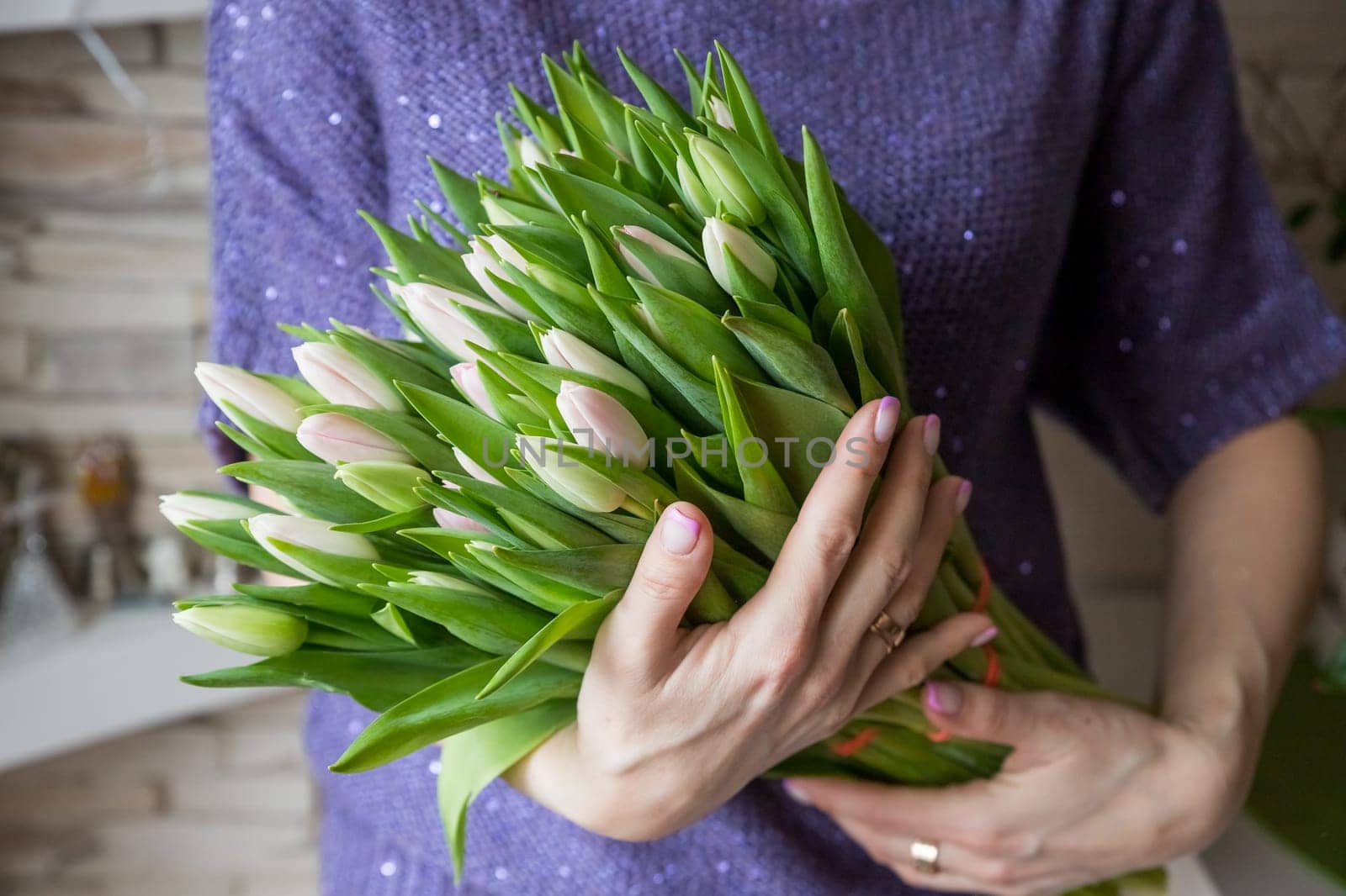 Young beautiful woman holding a spring bouquet of yellow tulips in her hand. Bunch of fresh cut spring flowers in female hands