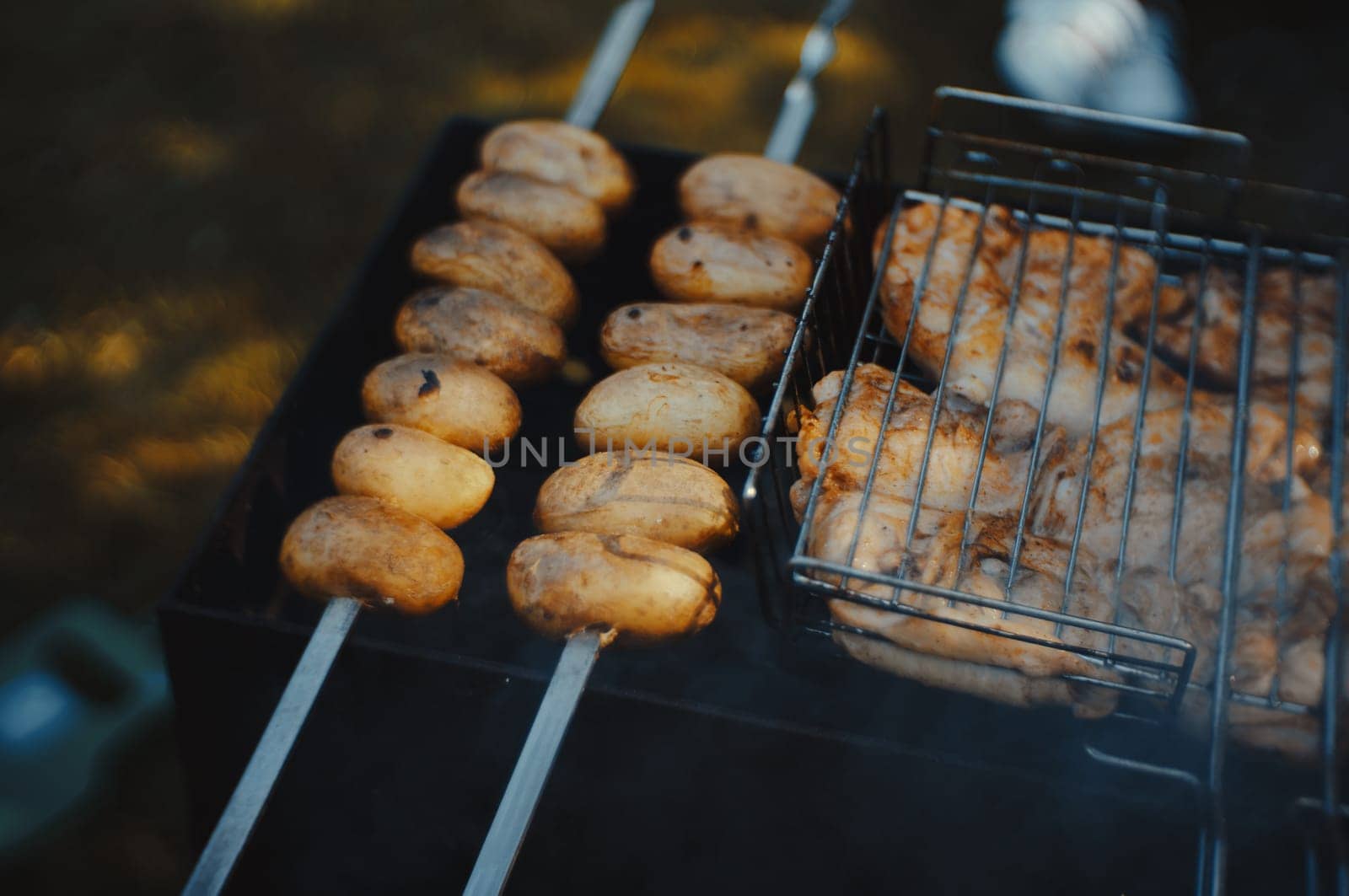 Potato skewers on burning coals on outdoor grill. by krol666