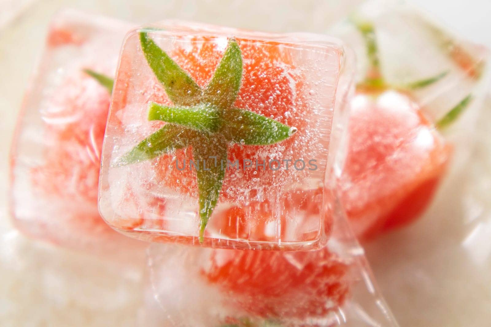 Photographic documentation of some small tomatoes inside an ice cube 