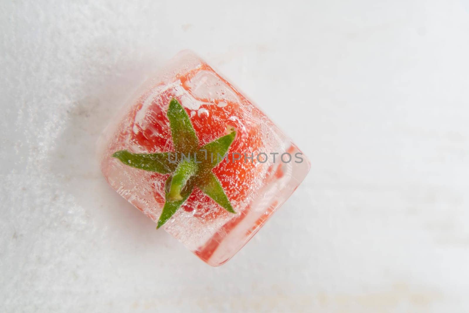 Photographic documentation of some small tomatoes inside an ice cube 