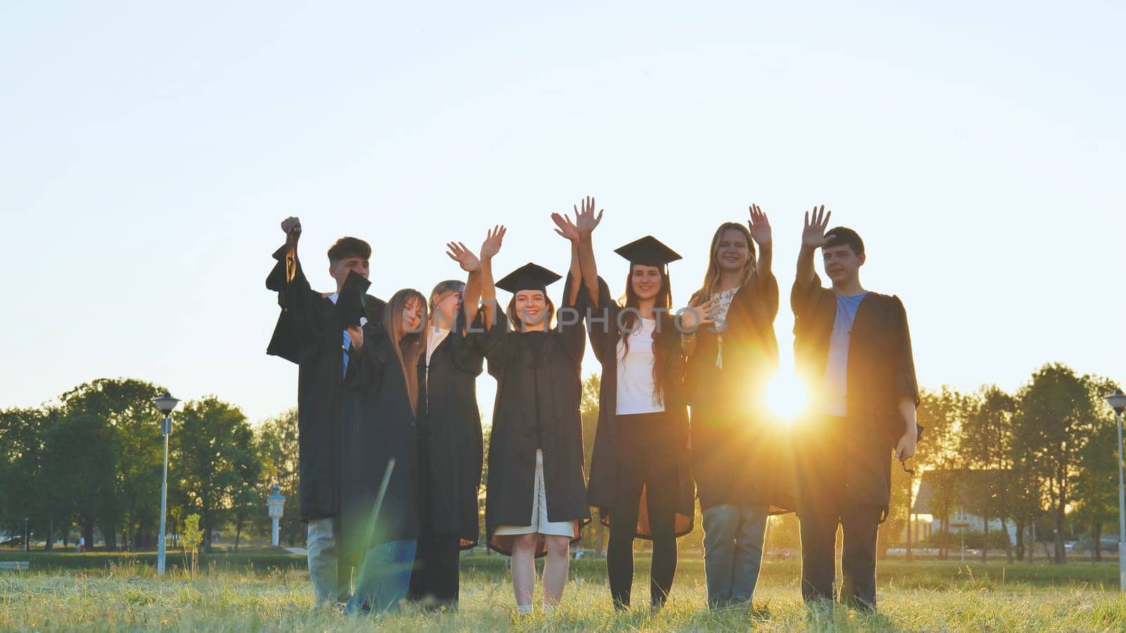 College alumni friends pose in the evening meadow. by DovidPro