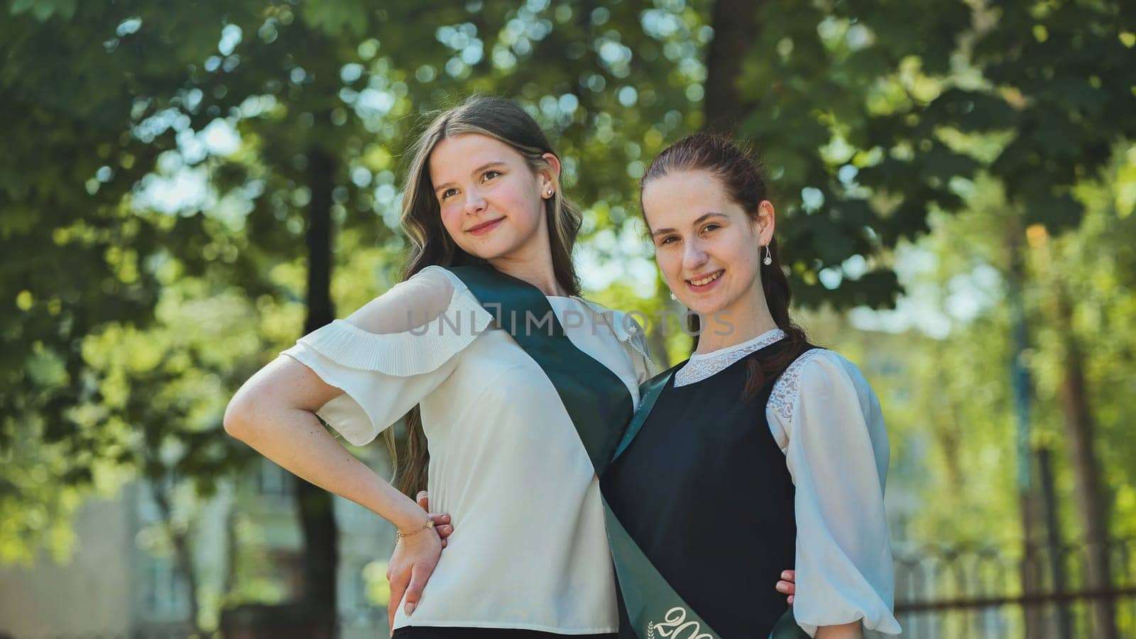 Two Russian schoolgirls graduate posing on a summer day