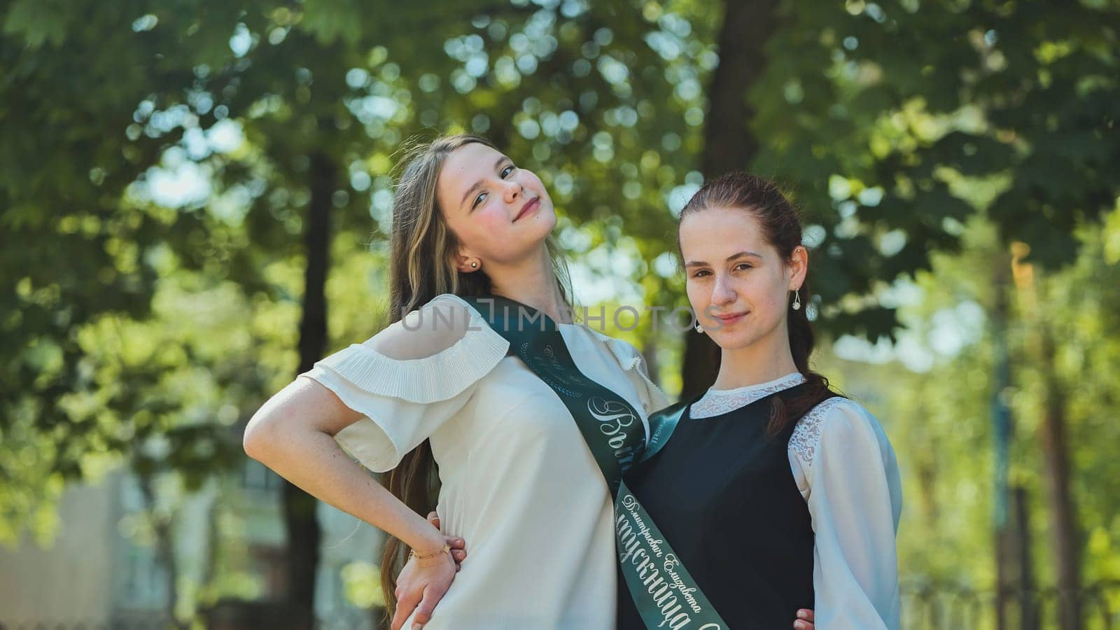 Two Russian schoolgirls graduate posing on a summer day
