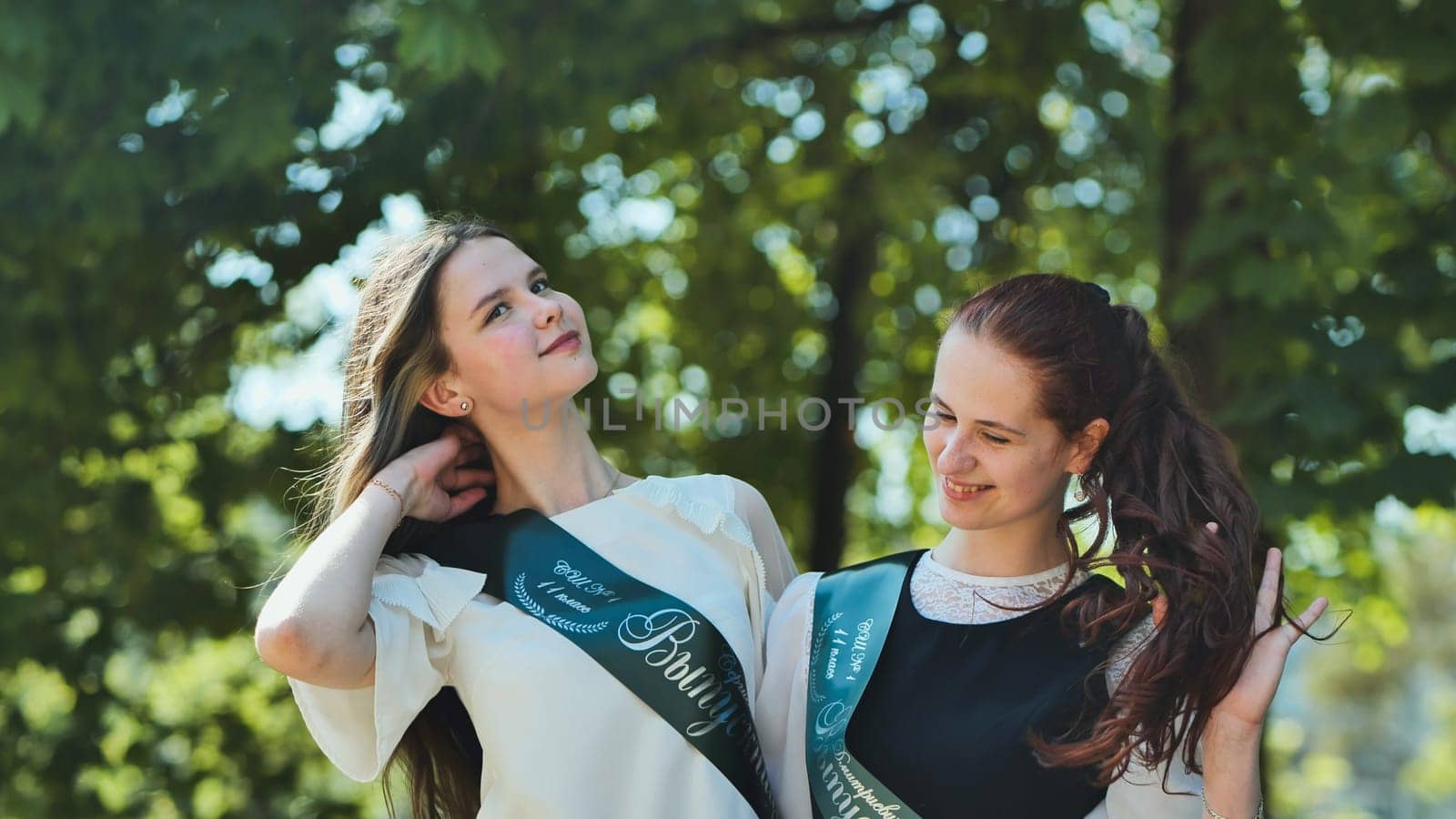 Russian girls graduate posing with a flyer and inscription - Graduate 2023 on graduation day
