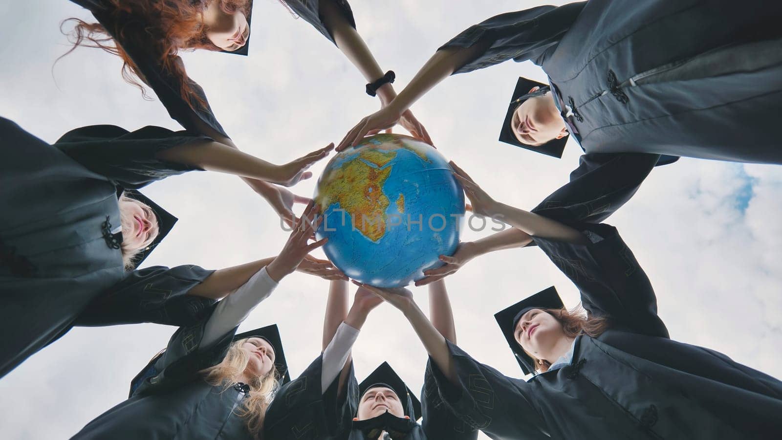 The concept of a world without war. College graduates holding a geographical globe of the world