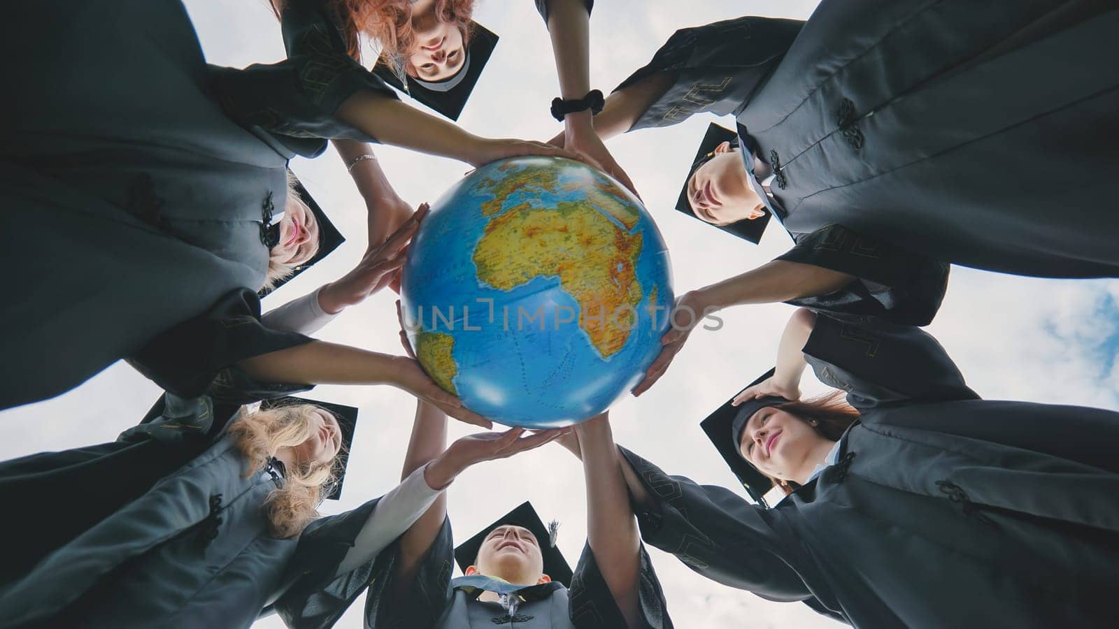 Graduating students twirl a geographic globe of the world in their hands