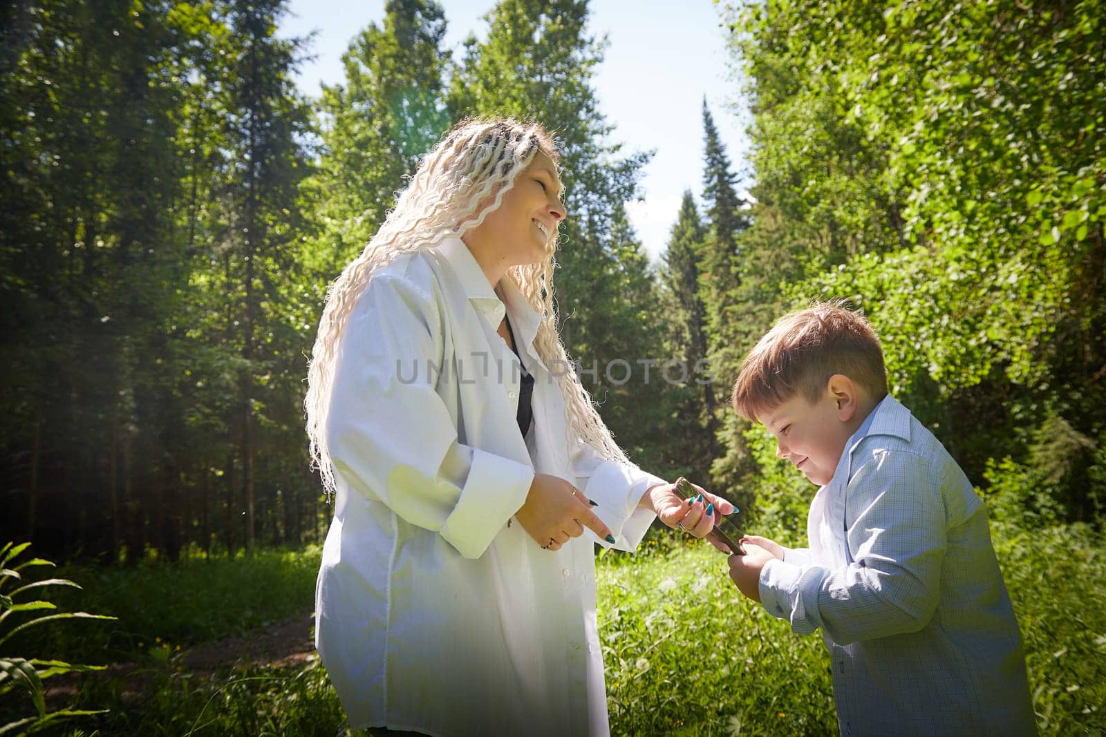 Young fat teenage boy playing with phone and mother swears, demands to stop it in a park. Blogger, gamer, streamer son online on Internet and conflict