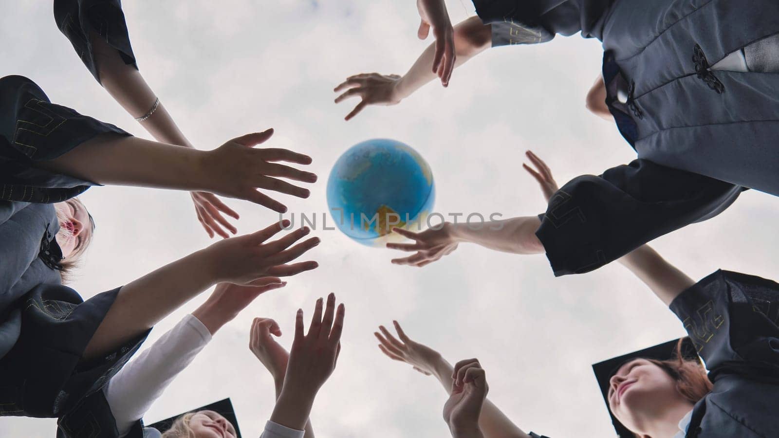 College alumni students toss a globe of the world into the sky. by DovidPro