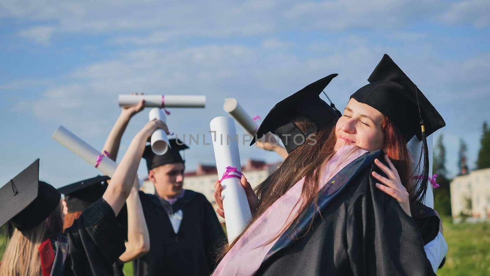Two college graduates girls hugging on a sunny day