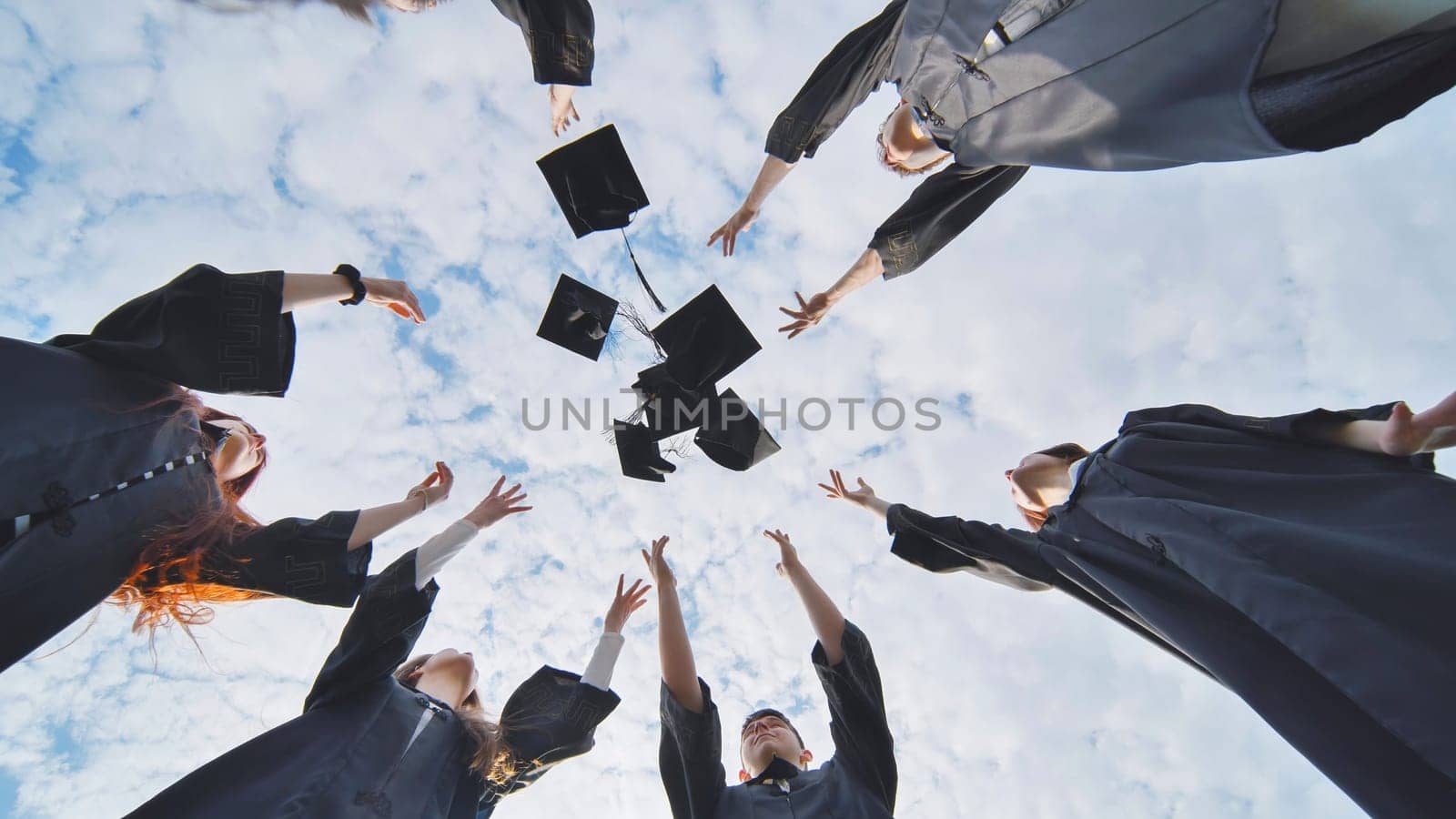 Happy college graduates tossing their caps up at sunset. by DovidPro