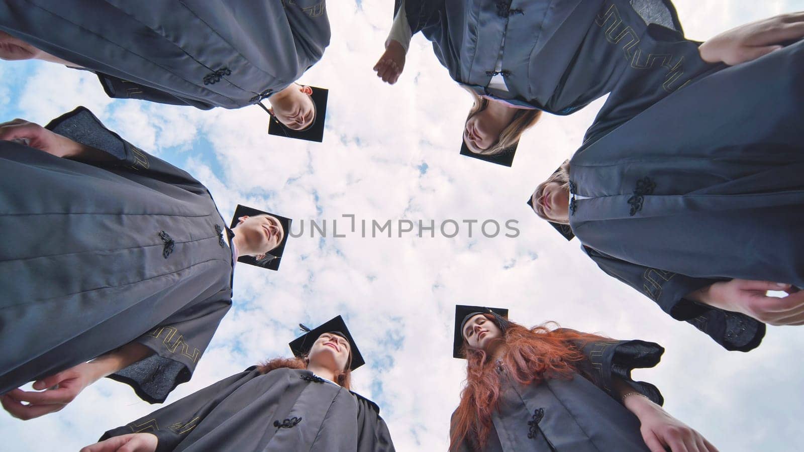 College students stand in a circle wearing black robes