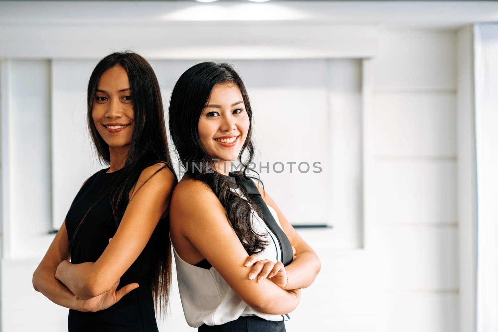 Two young Asian businesswomen sitting in office. Business friends and community concept. uds