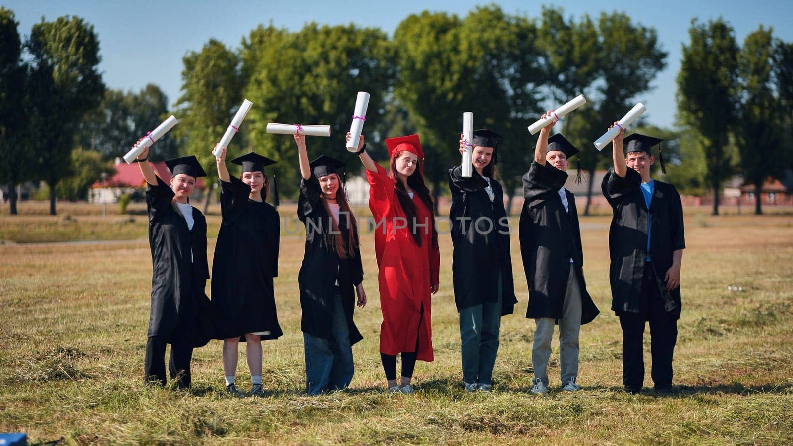 group of multiracial graduates holding diploma. by DovidPro