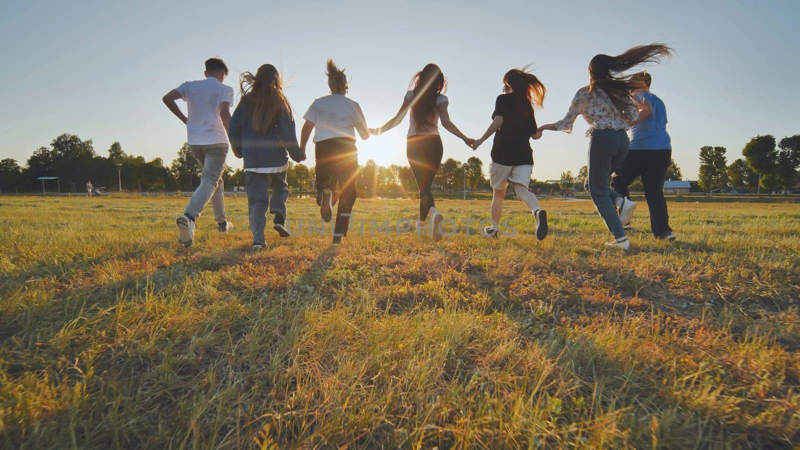 Young boys running at sunset across the field holding hands