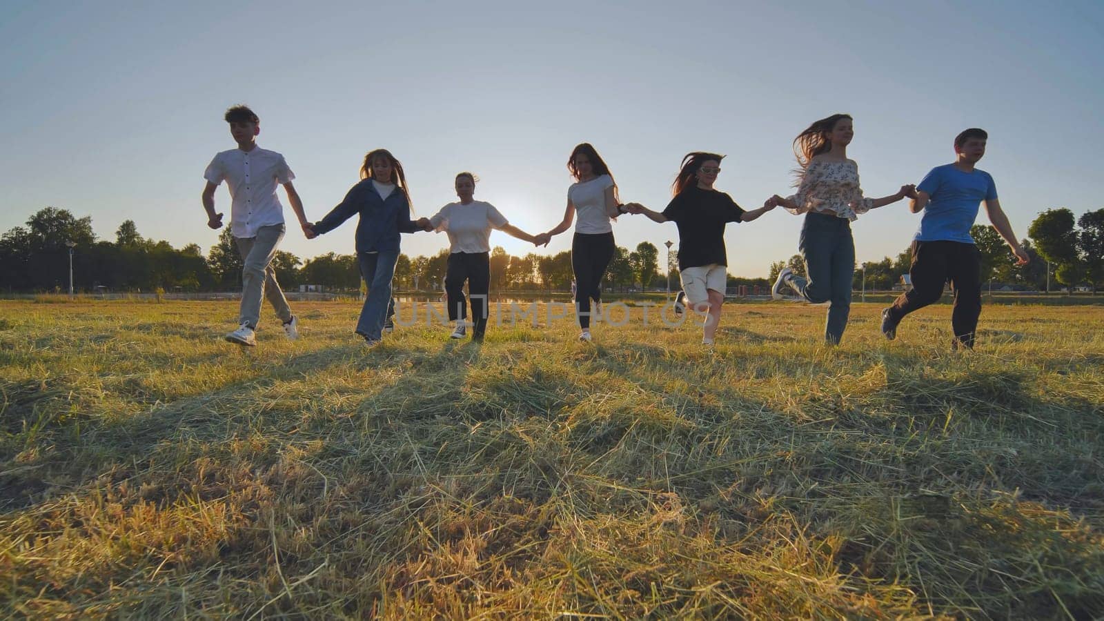 Children running on meadow at sunset. by DovidPro