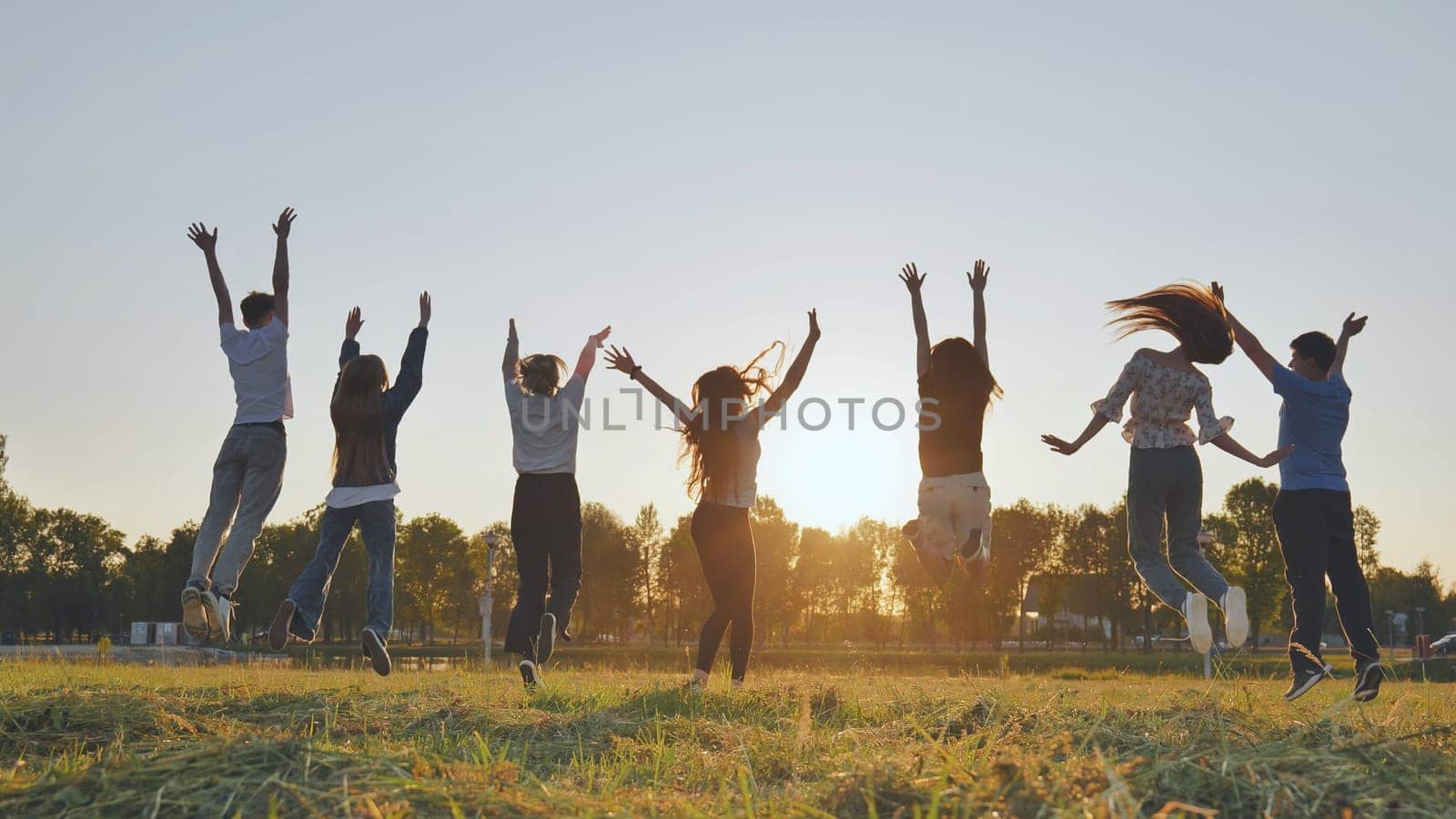 Merry friends jumping around at sunset