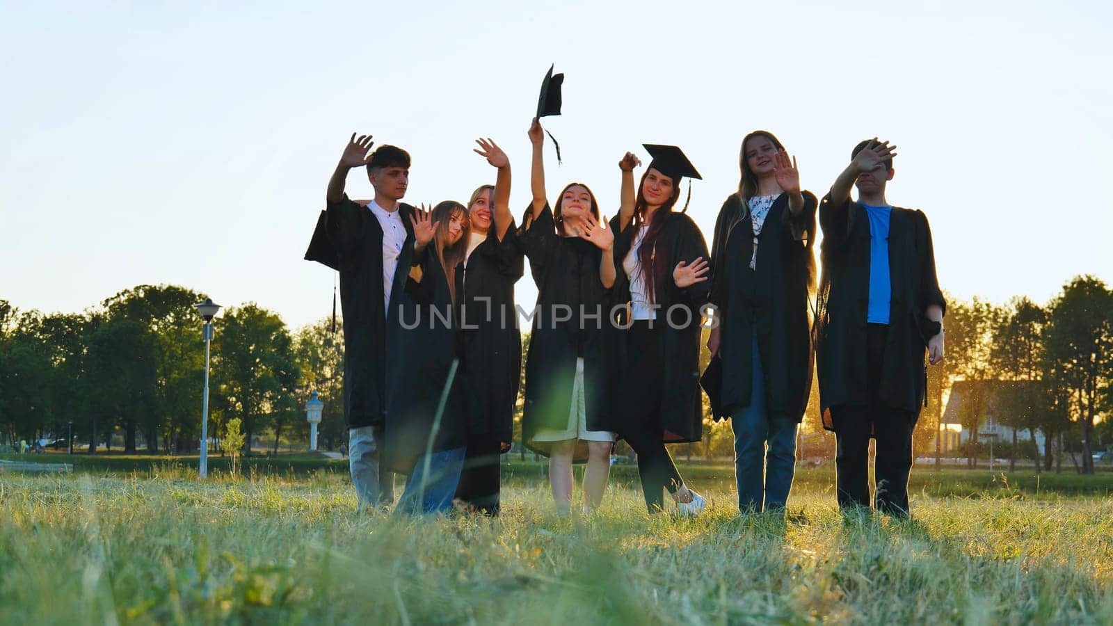 Student alumni waving at sunset