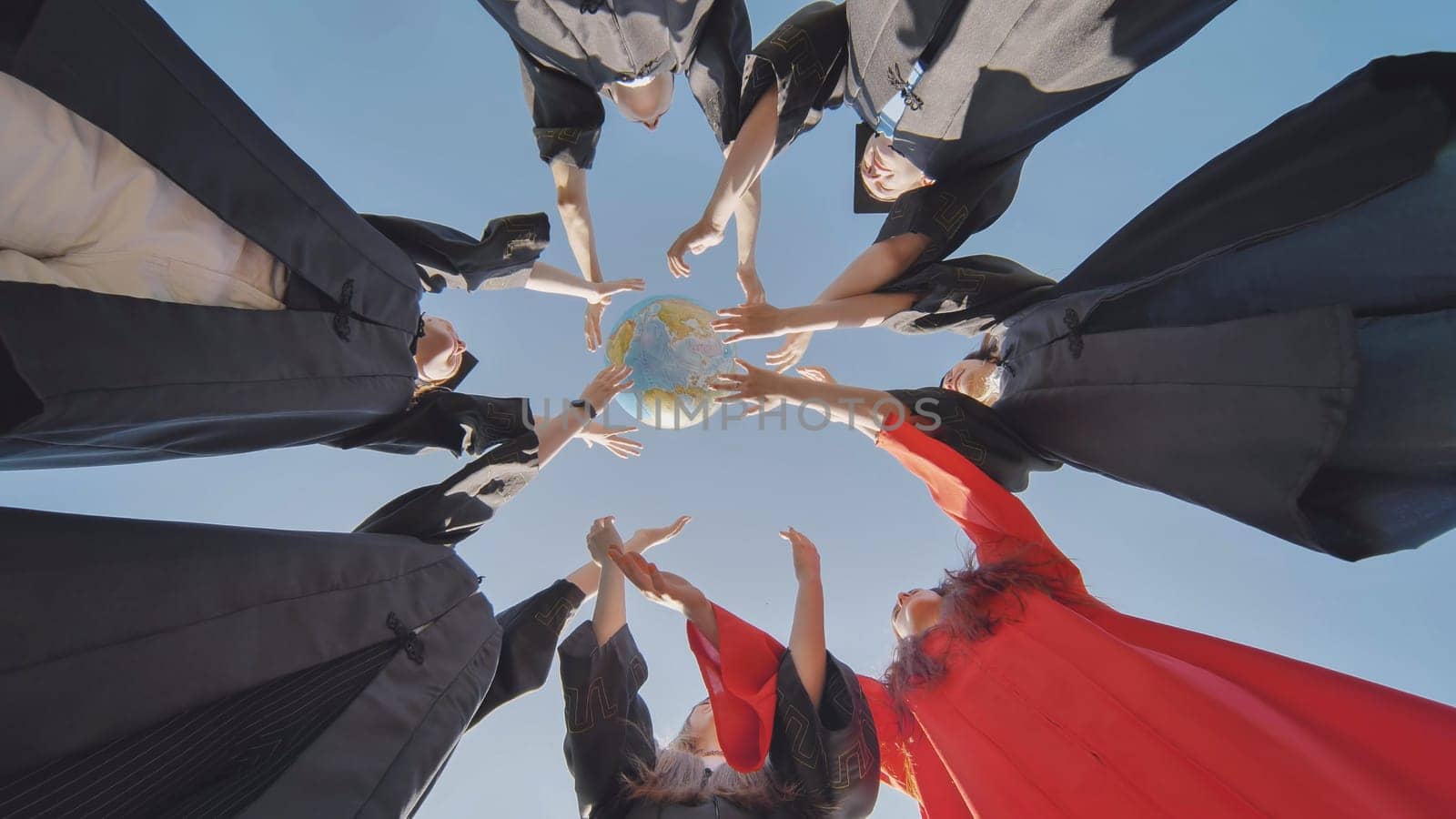 College alumni students toss a globe of the world into the sky