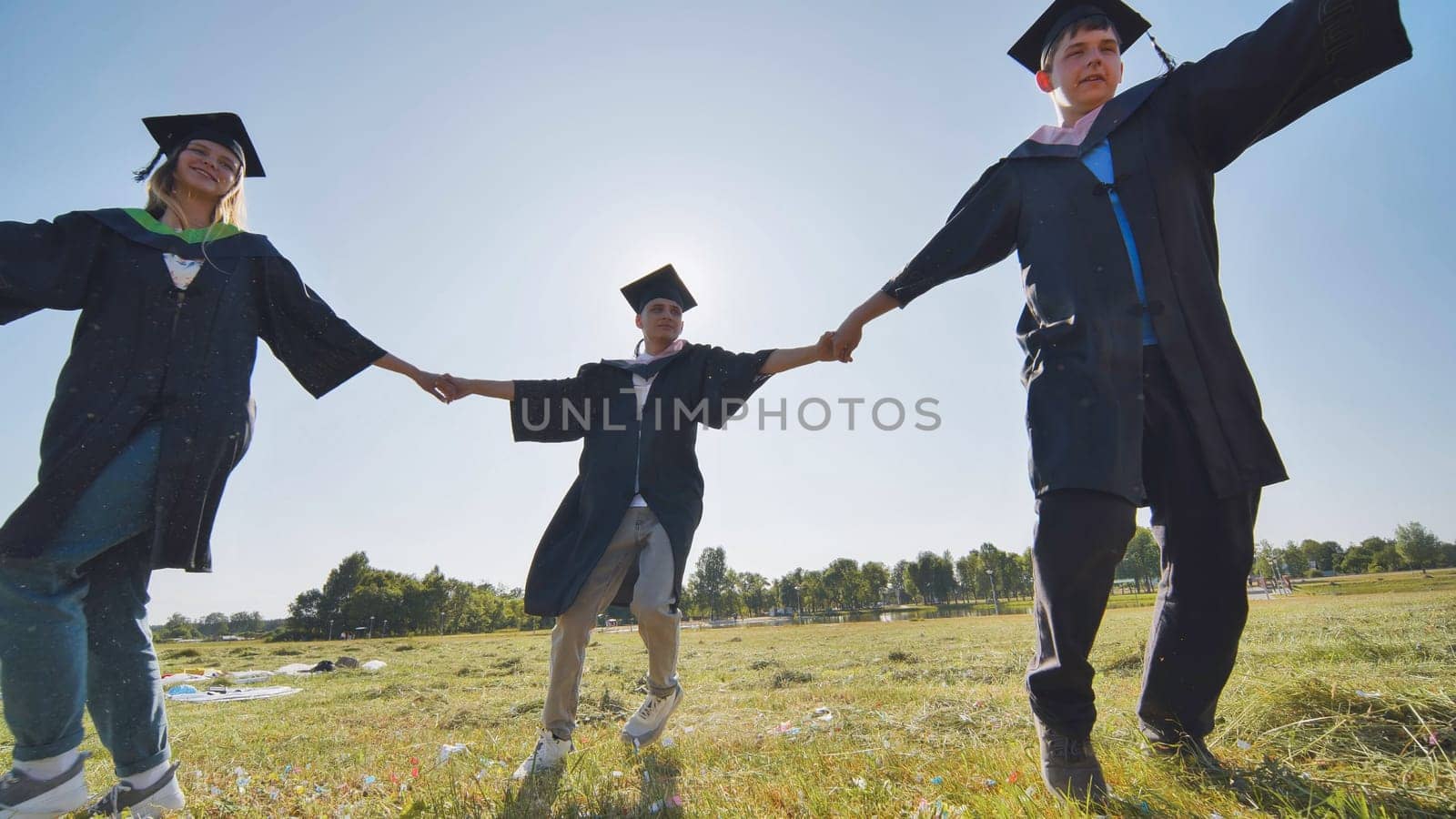 College graduates holding hands run in a round dance