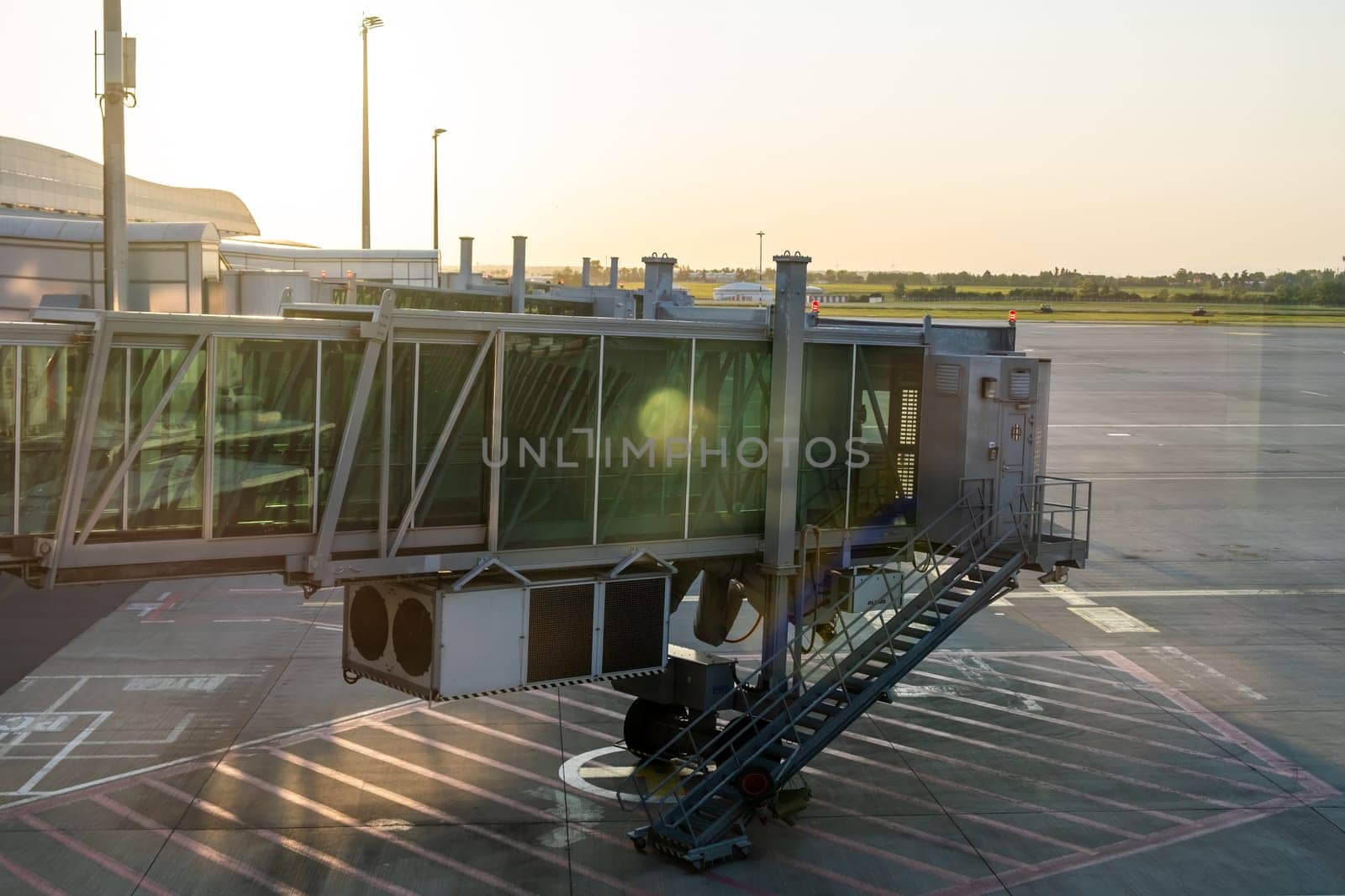 Passenger boarding bridge at airport apron in sun light.