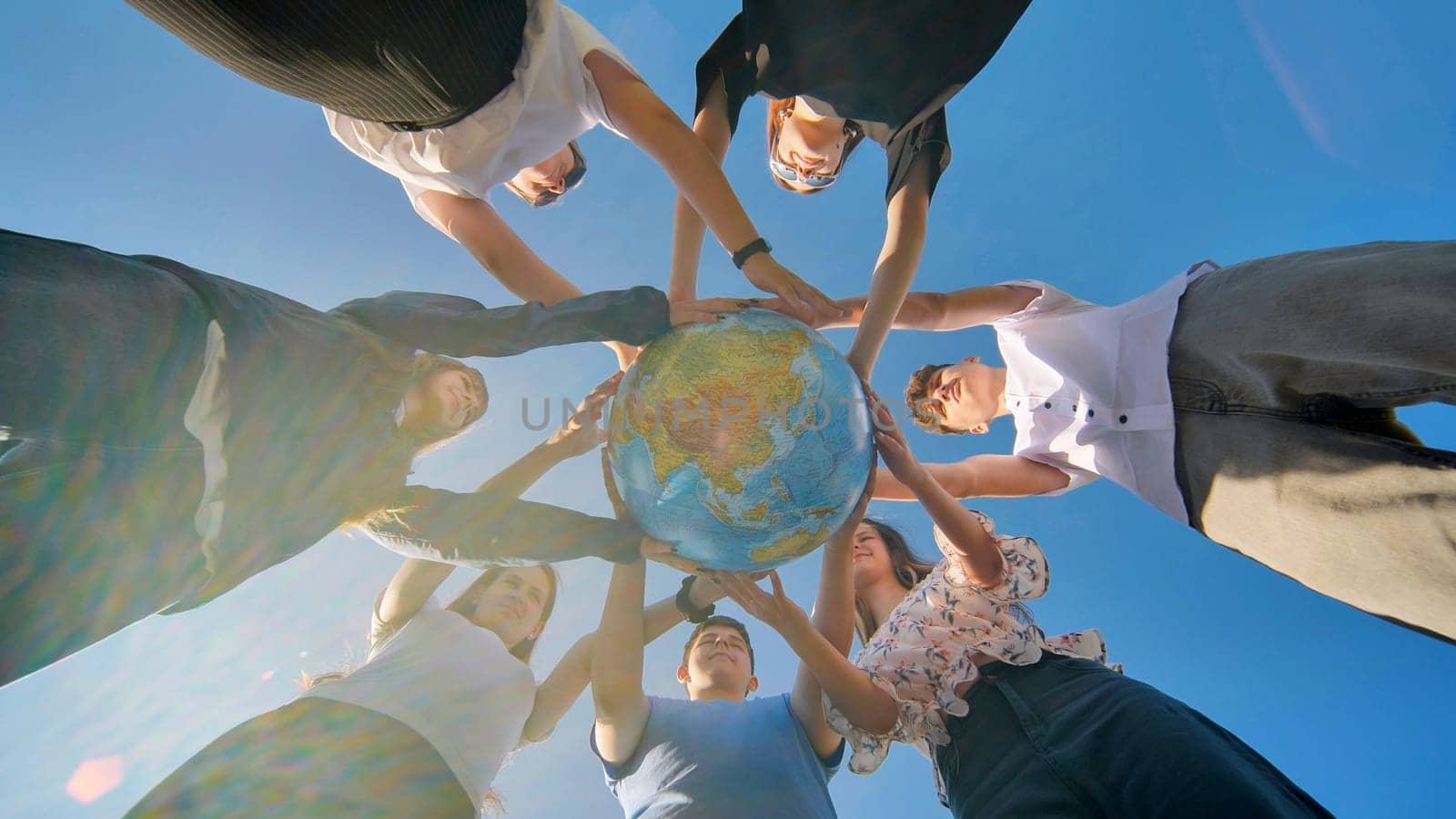 Friends holding a geographical globe in their hands. The concept of keeping the world safe. by DovidPro