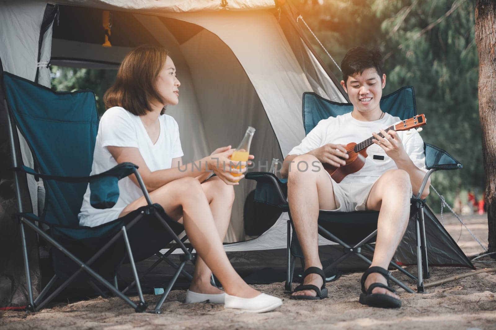 Love-filled moments at the campsite, An Asian couple playing the ukulele and singing, surrounded by the warmth of their tent. Their smiles reveal the joy of togetherness. Happiness is in the air. by Sorapop