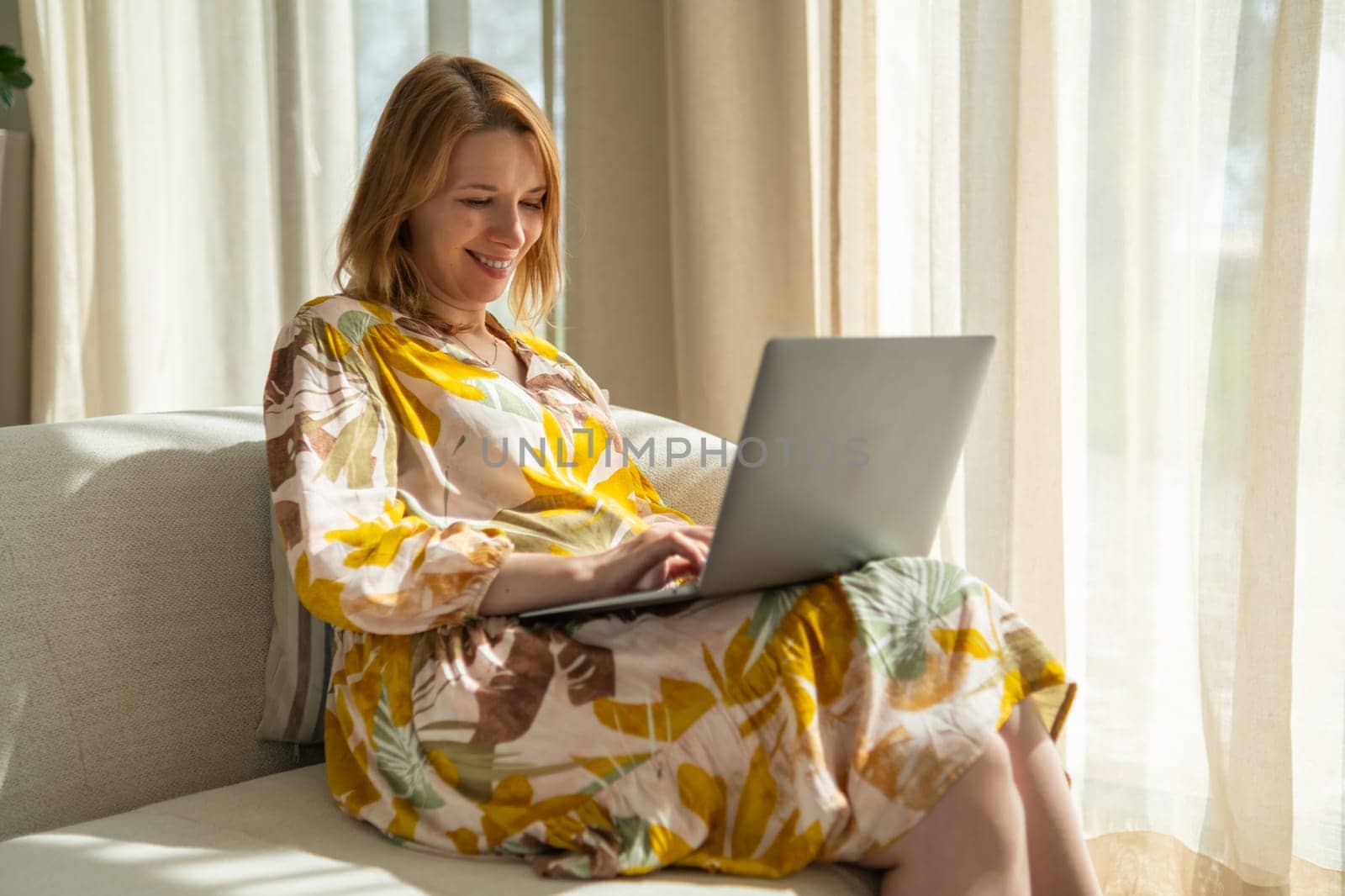 Smiling blonde woman working in the modern interior and using a laptop.